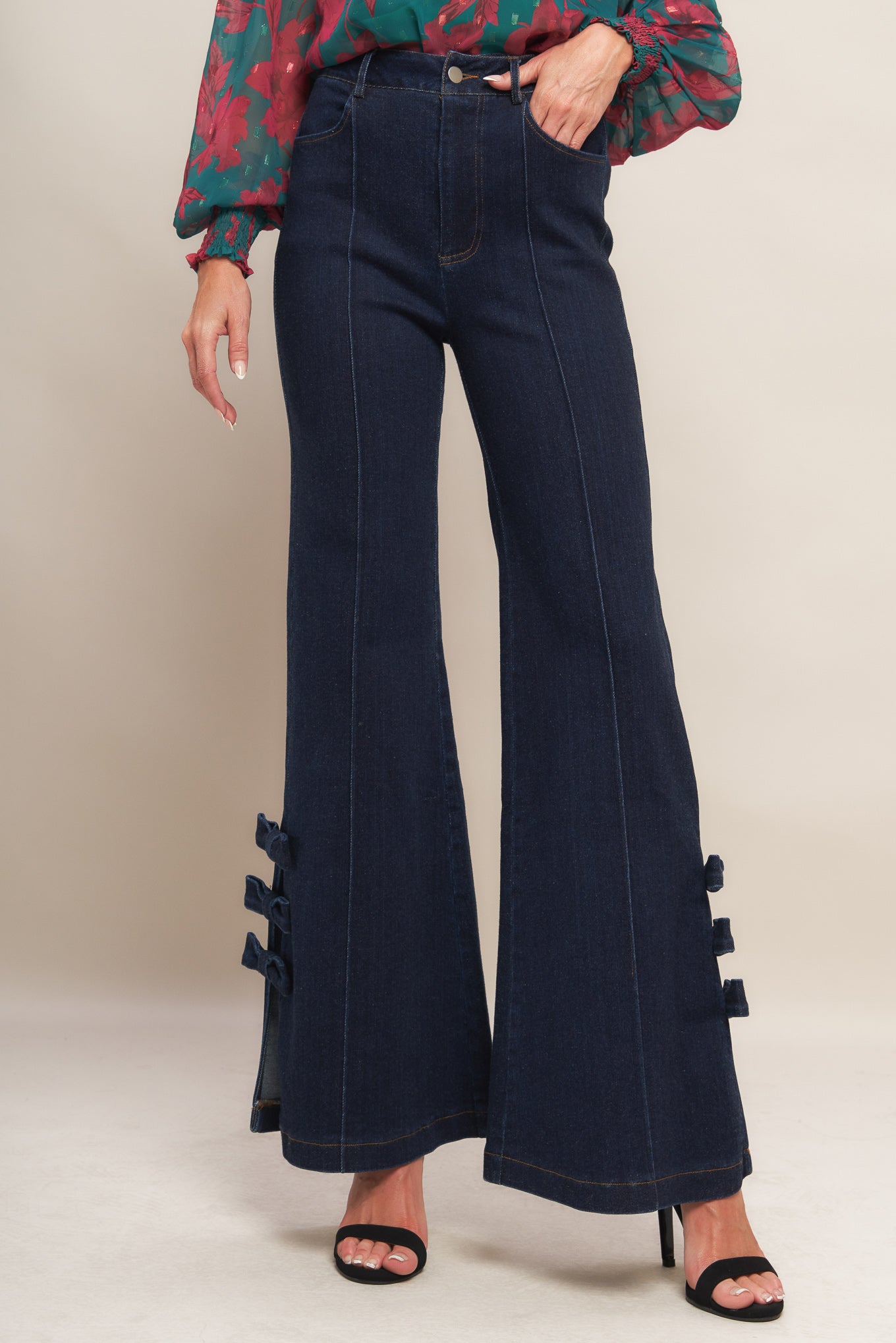 A washed denim pant featuring front closure, side pocket, flare leg with bow tie detail