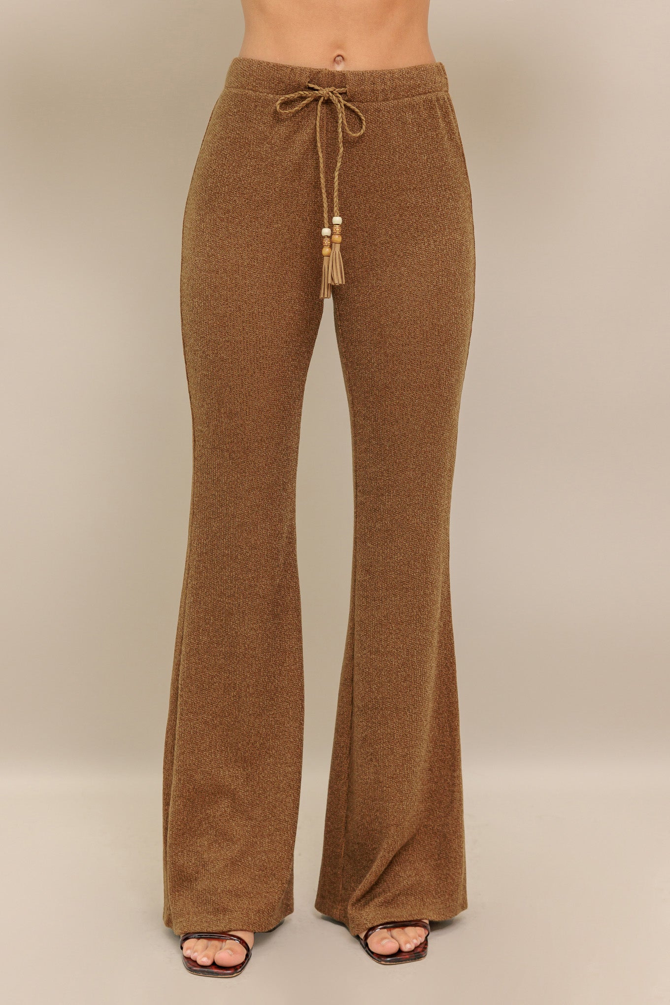 A solid knit pant featuring elasticized waist, flare leg and tassel tie.
