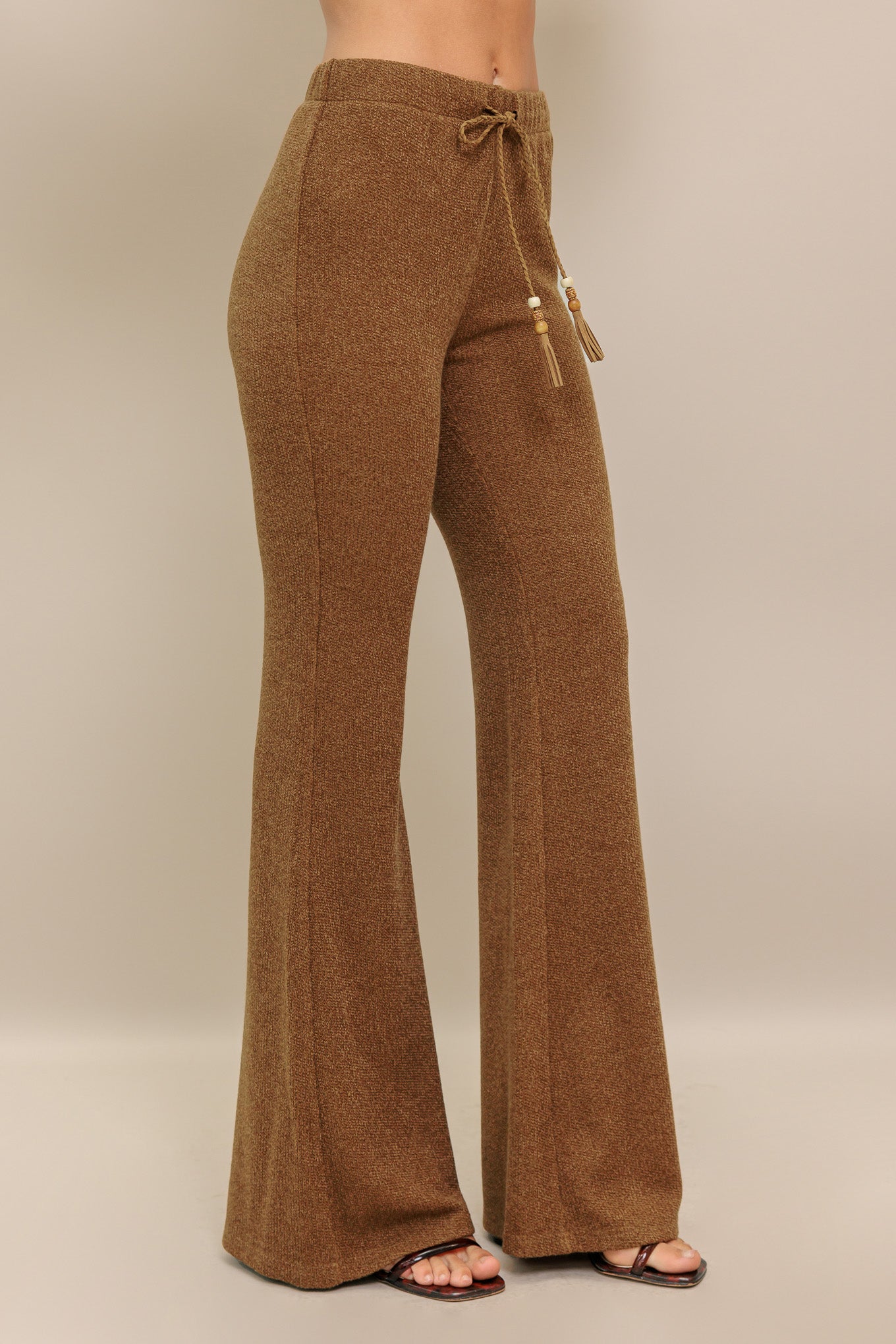 A solid knit pant featuring elasticized waist, flare leg and tassel tie.