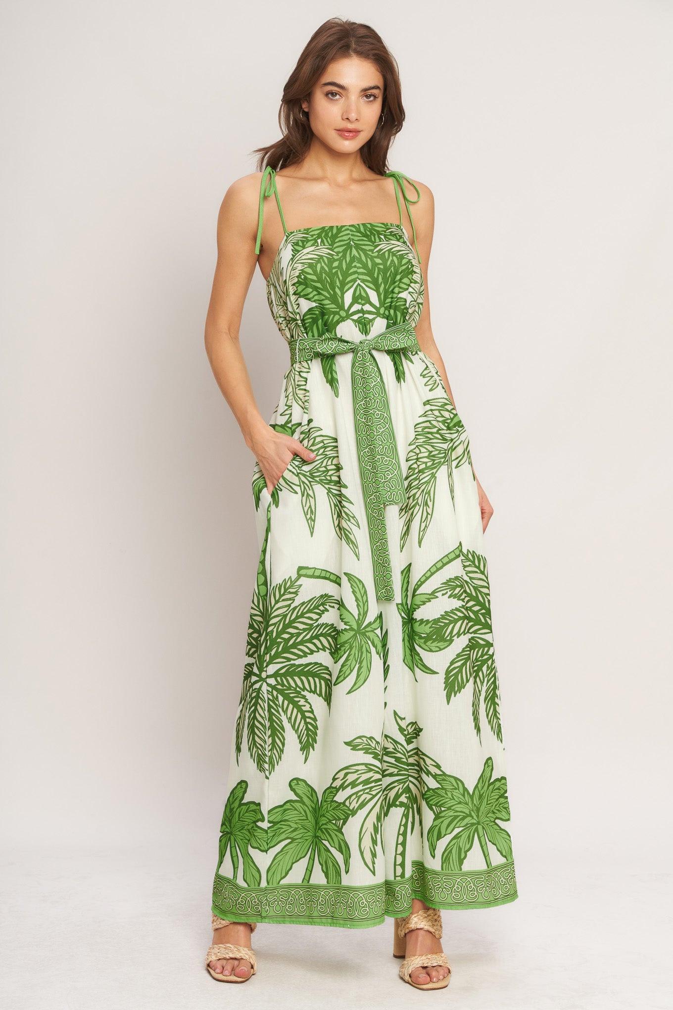 Woman wearing a green and white leaf-patterned dress on a plain background