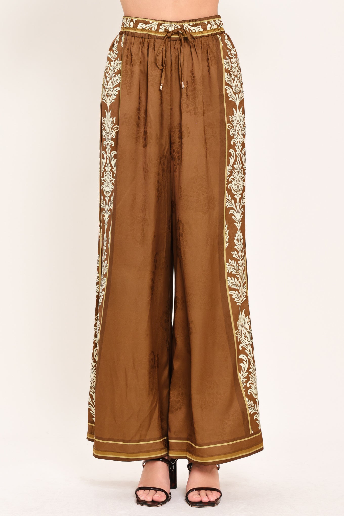 Woman wearing camel brown wide-leg pants with white floral embroidery on the side and waistband | Flying Tomato