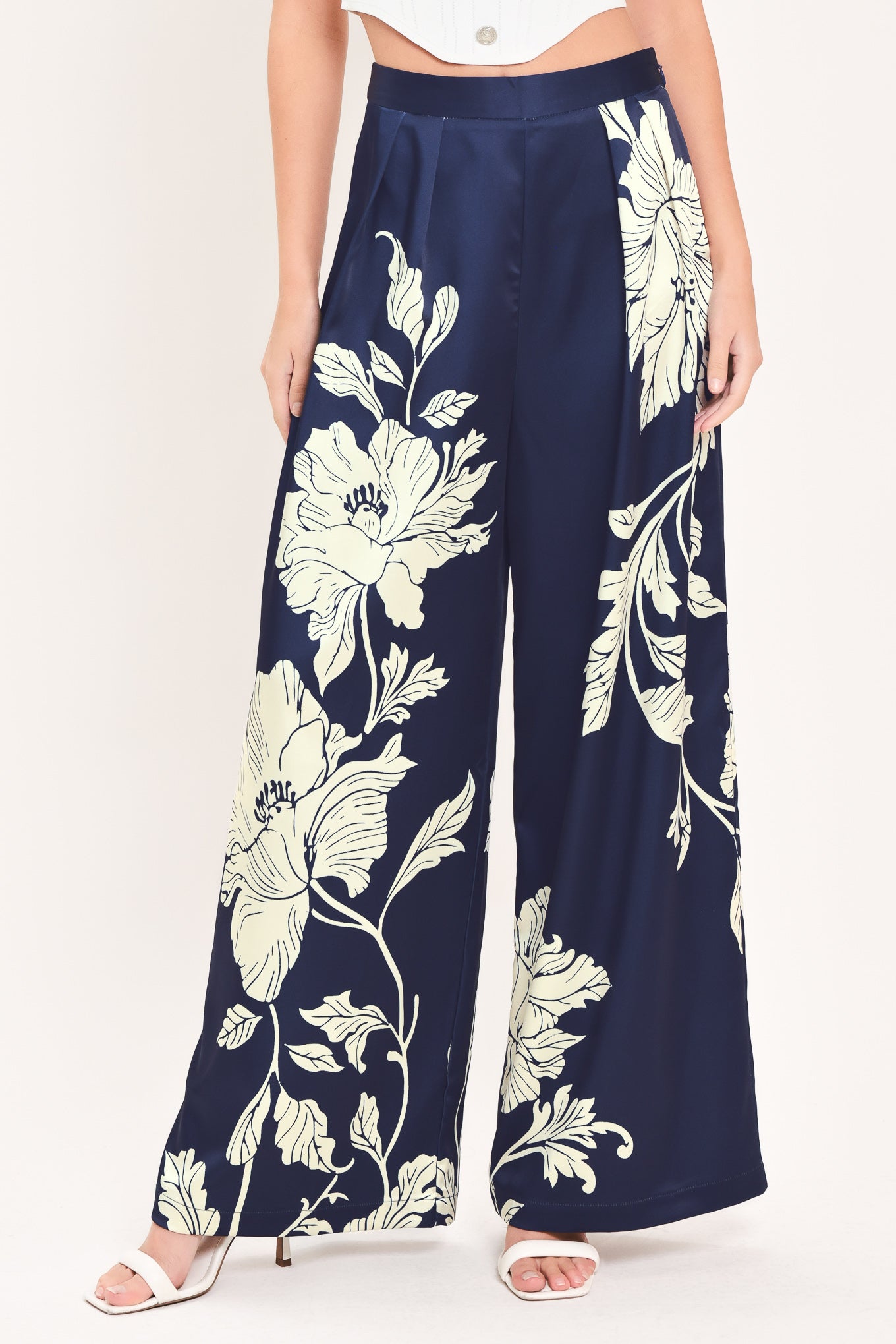 A woman wearing navy blue wide-leg pants with a large cream floral print | Flying Tomato