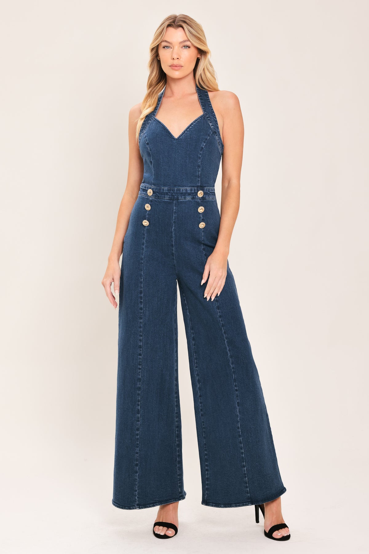 Woman wearing a denim jumpsuit featuring halter neckline, front button detail, wide leg, bare back and zipper closure | Flying Tomato