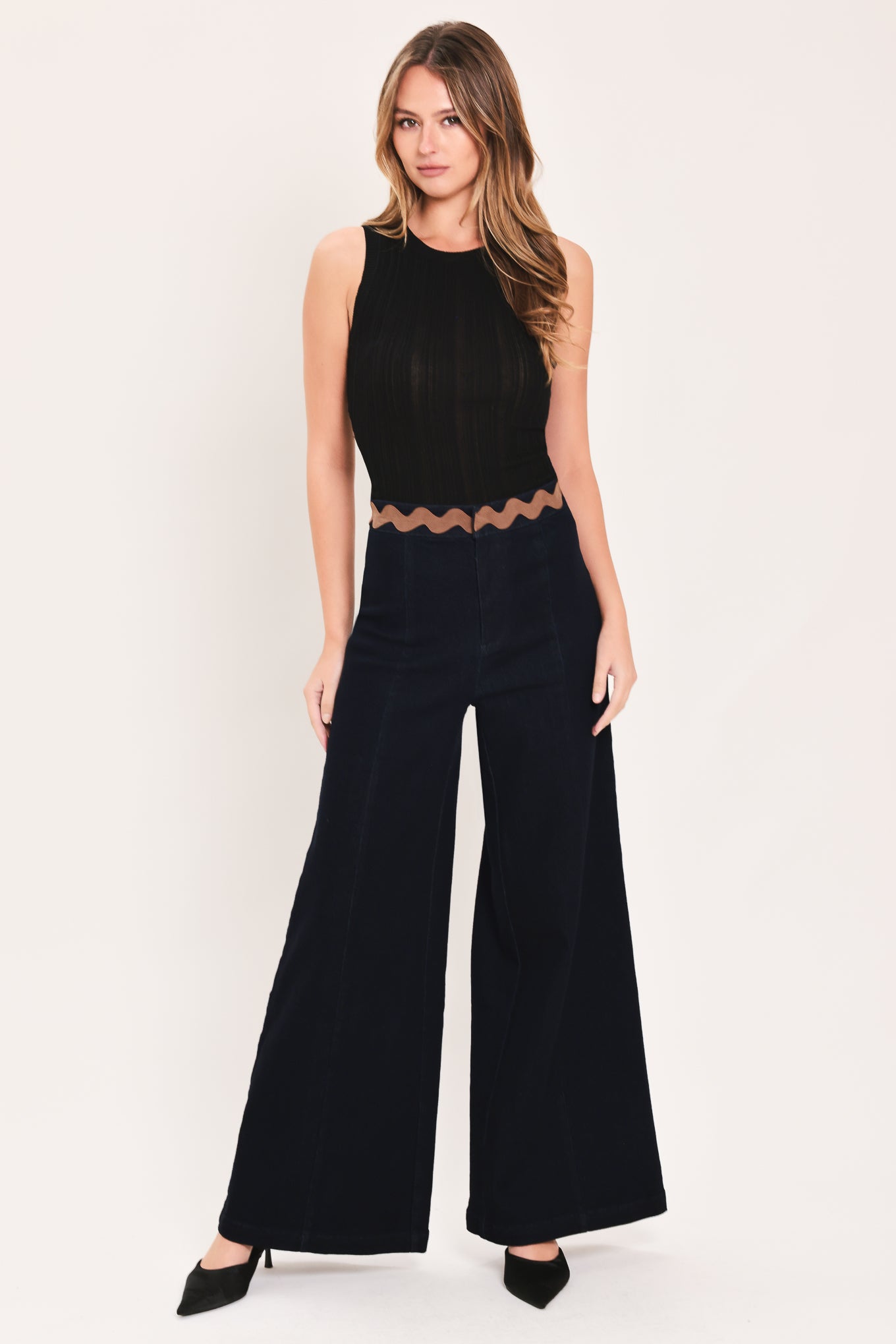 A model is wearing a pair of wide-leg navy blue pants with a distinctive scalloped brown waistband | Flying Tomato