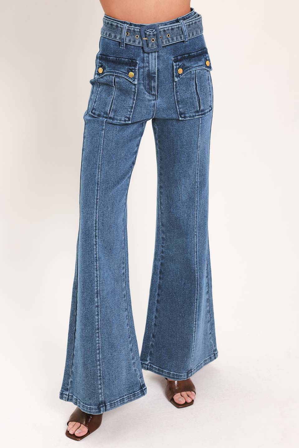 A woman wearing blue high-waisted flare jeans with front flap pockets and gold-tone button details | Flying Tomato