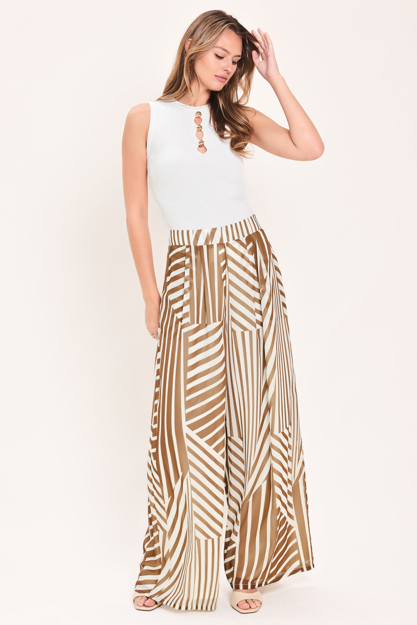 Woman wearing a pair of high waisted flowy wide leg pants with a geometric mocha and white pattern | Flying Tomato
