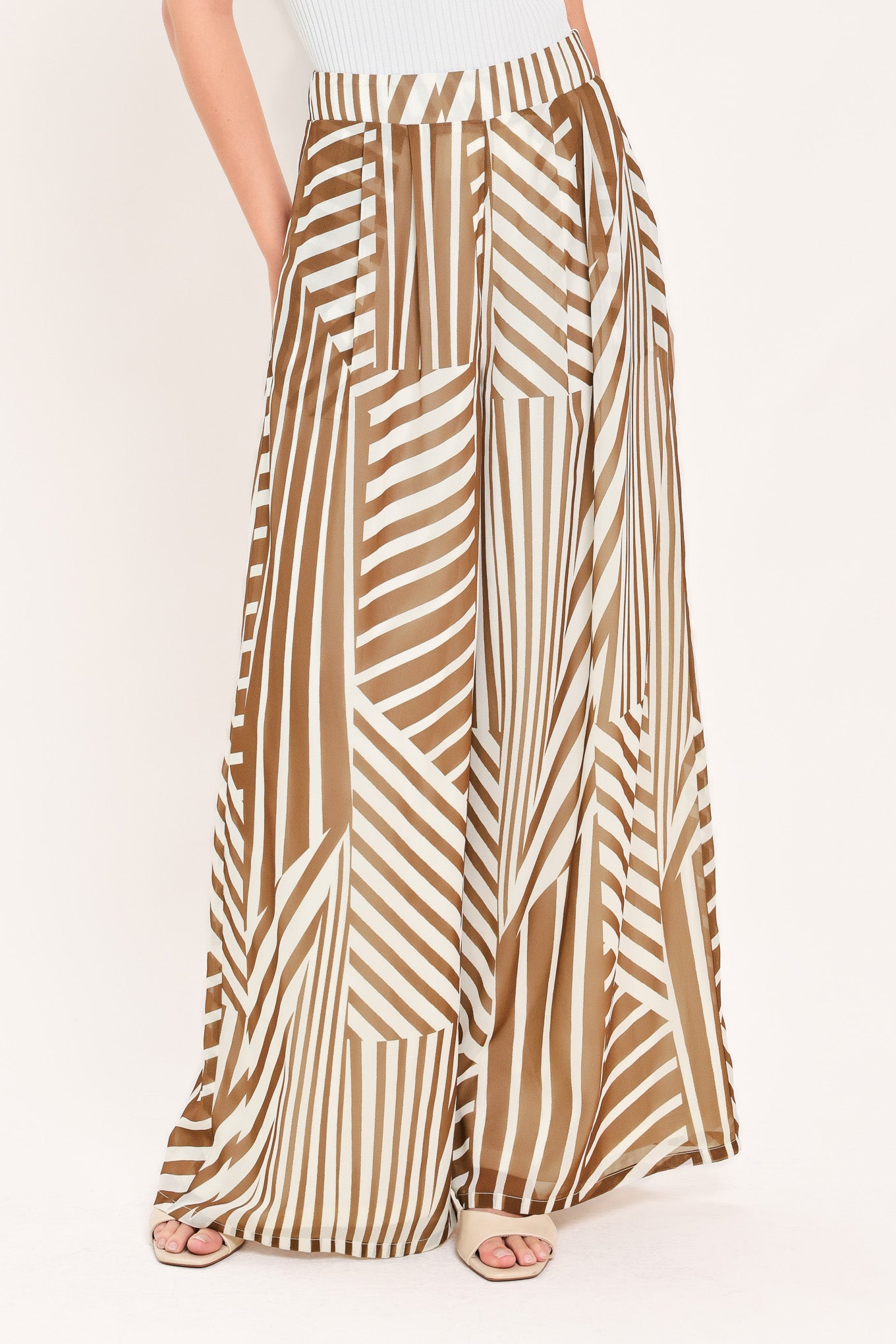 Woman wearing a pair of high waisted flowy wide leg pants with a geometric mocha and white pattern | Flying Tomato