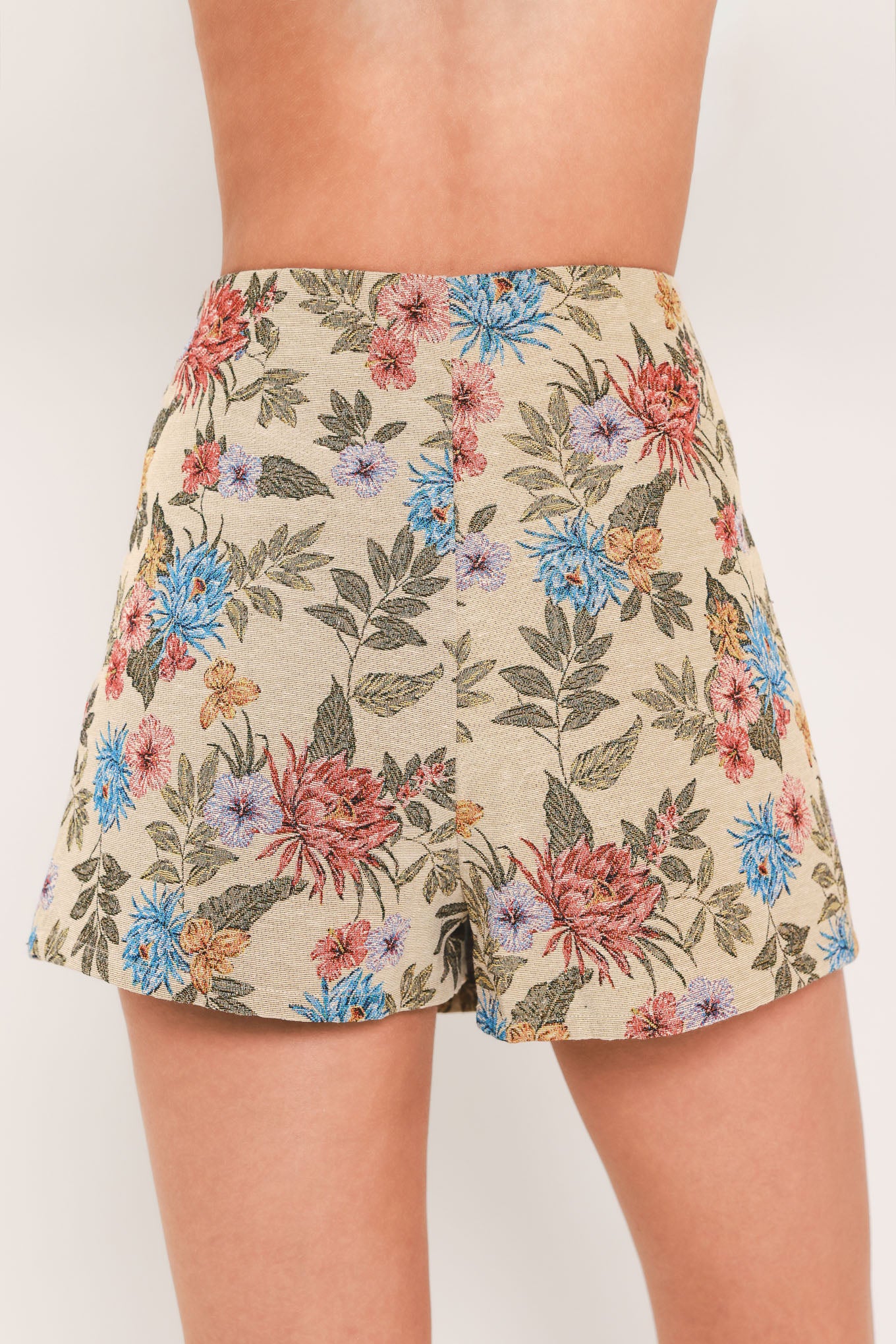 A woman wearing a beige woven jacquard skort with blue and pink flowers and green leaves | Flying Tomato