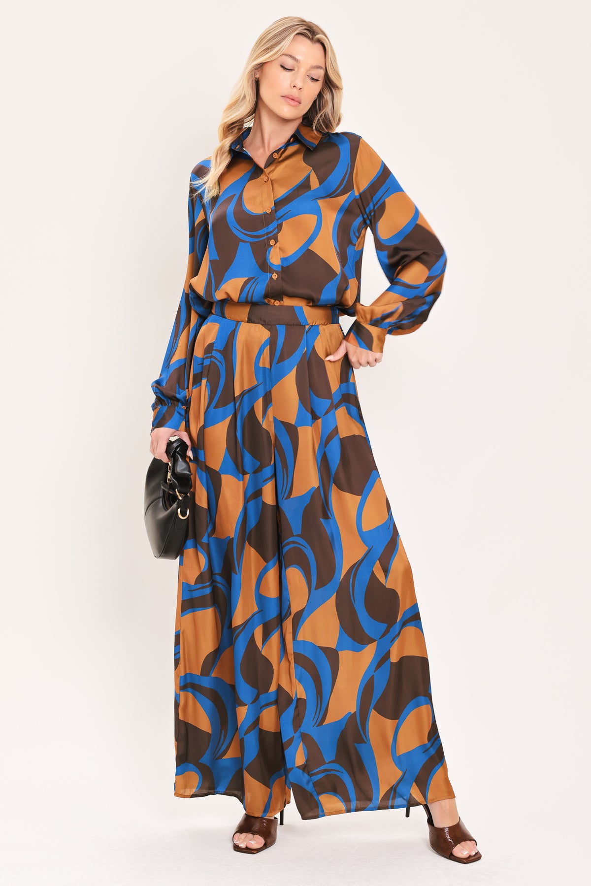 A woman modeling wide-leg pants with a bold abstract swirl pattern in brown, blue, and black | Flying Tomato