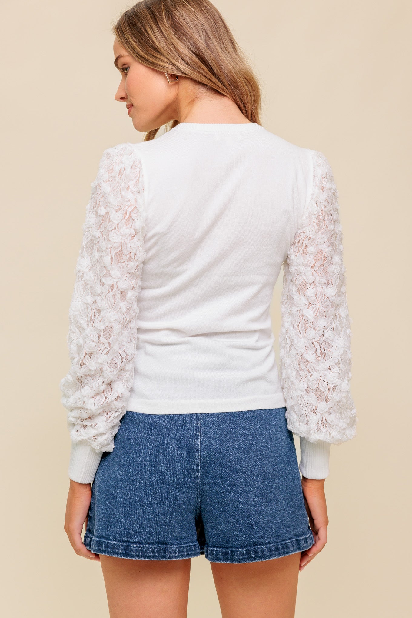 A sweater knit top featuring round neckline with contrasting sleeve