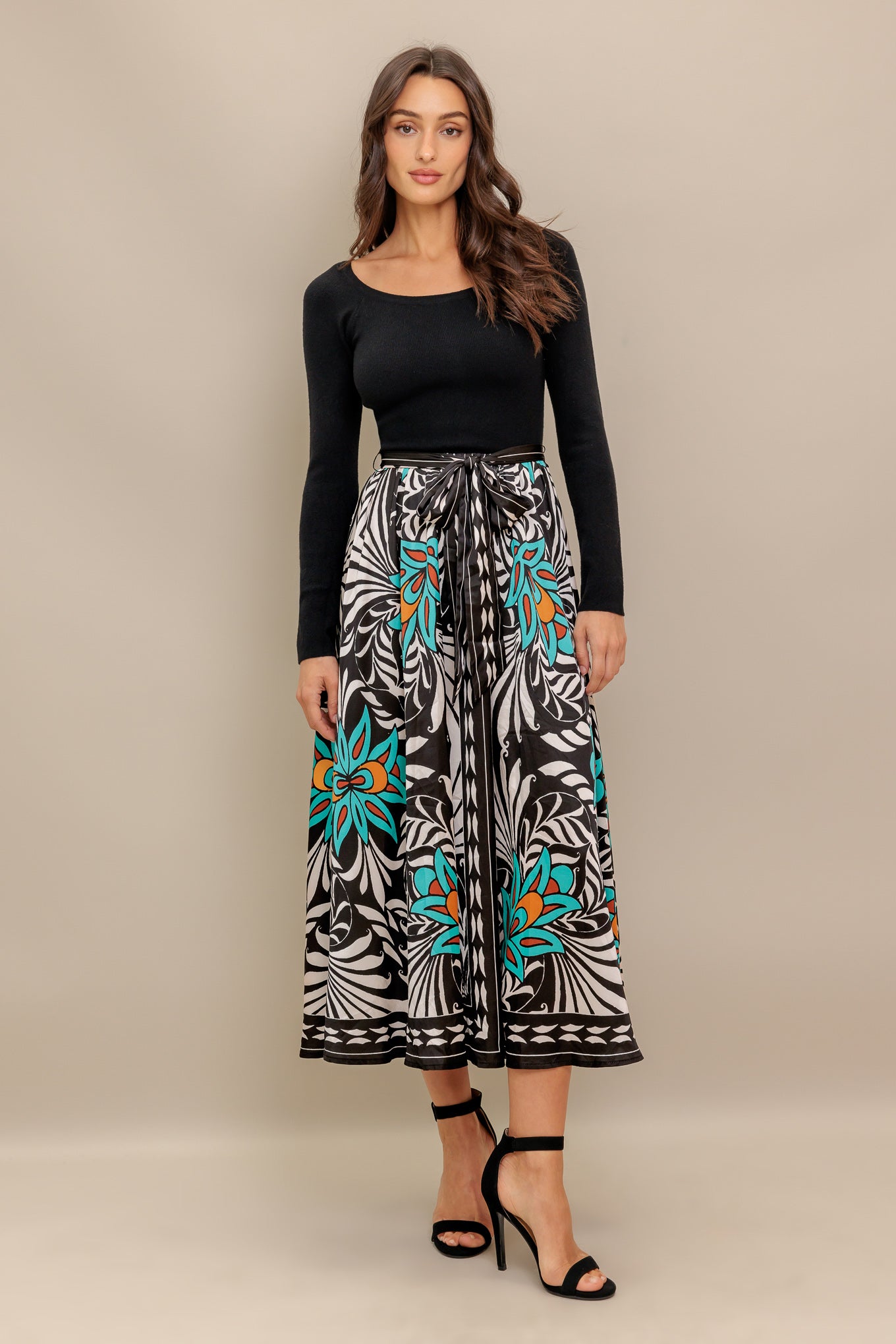 A midi dress featuring sweater top with long sleeve, self sash and printed woven skirt