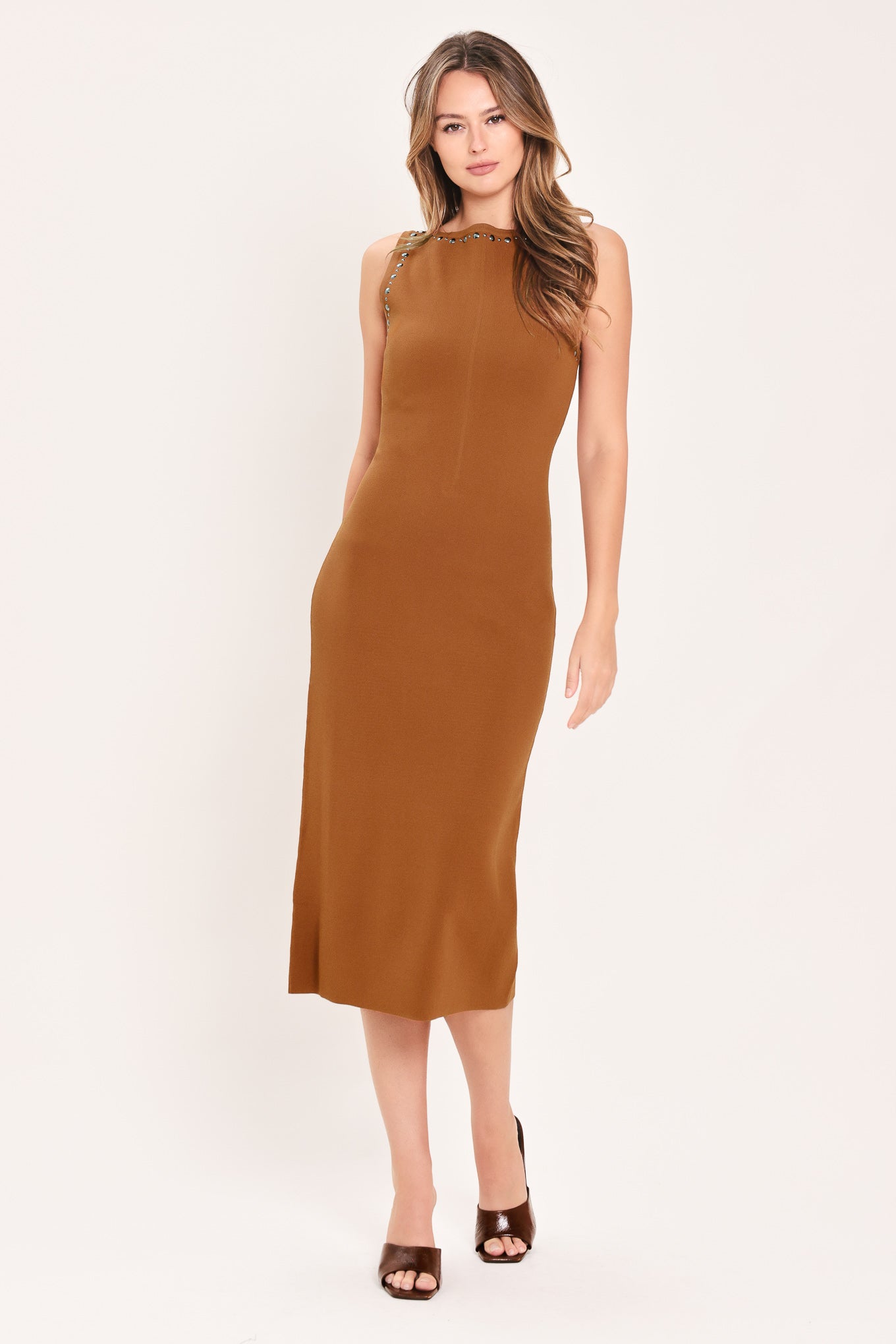 A woman wearing a sleeveless, high-neck, sweater knot bodycon midi dress in a warm camel brown color | Flying Tomato