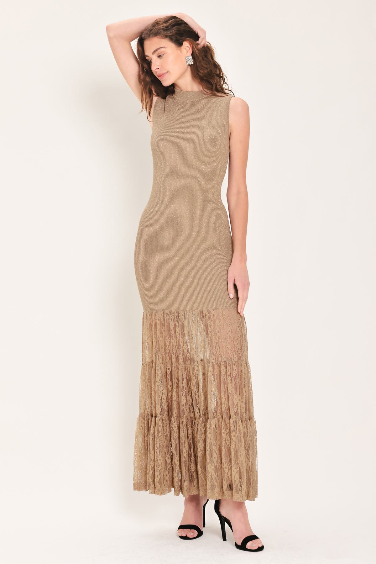 Woman wearing a sleeveless mock neck beige/gold metallic maxi dress with lace tiered skirt starting at the thighs | Flying Tomato