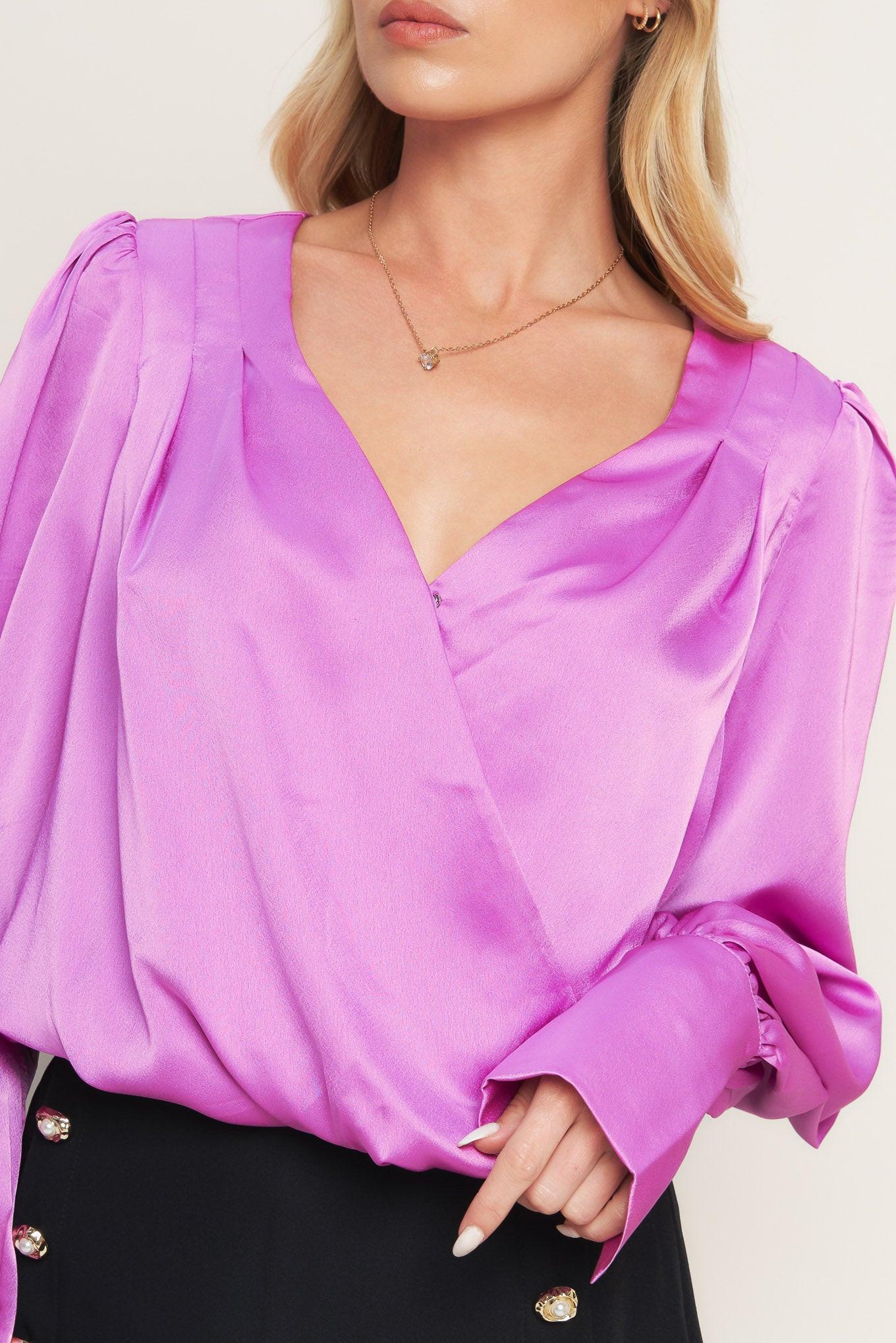 A solid woven top featuring surplice neckline, long sleeve with cuff and elasticized waist