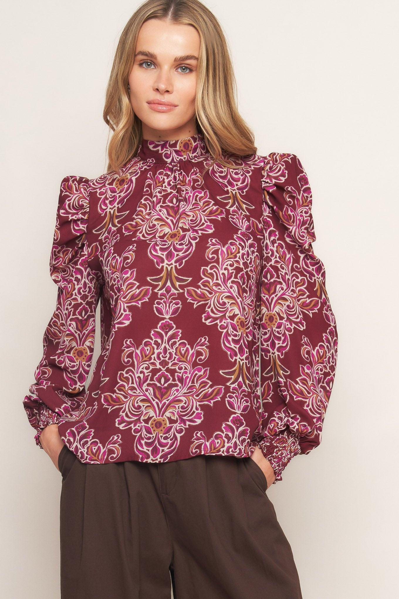 A printed woven top featuring high neckline, long puff sleeve and back neck tie closure