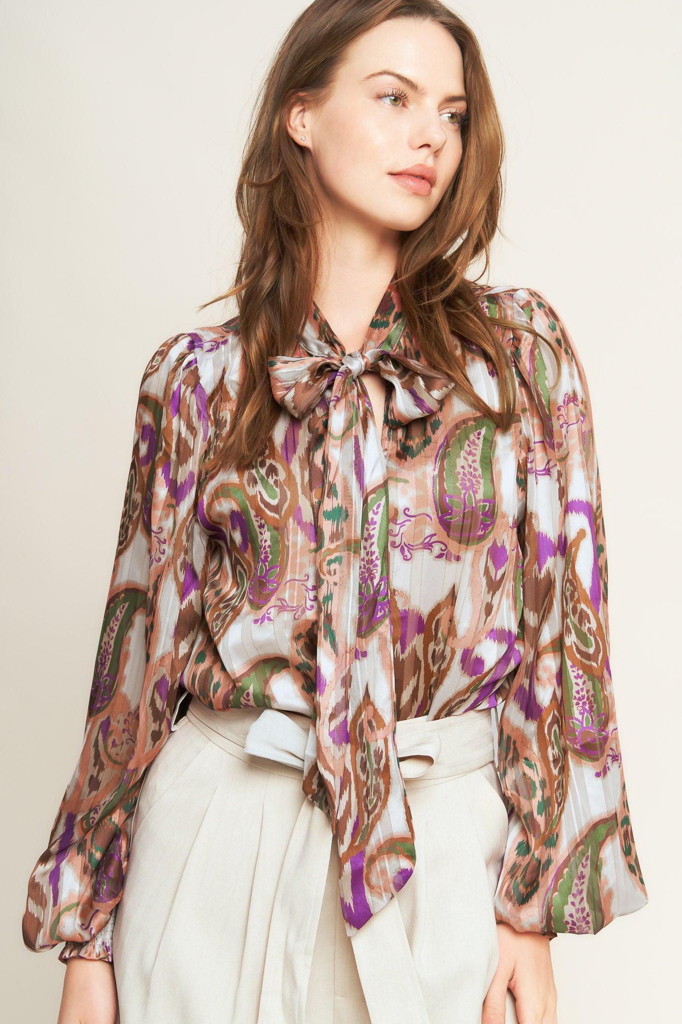 Woman wearing a patterned blouse with a bow tie against a plain background. A printed woven top featuring front bow tie and long sleeve with smocked cuff - FLYING TOMATO