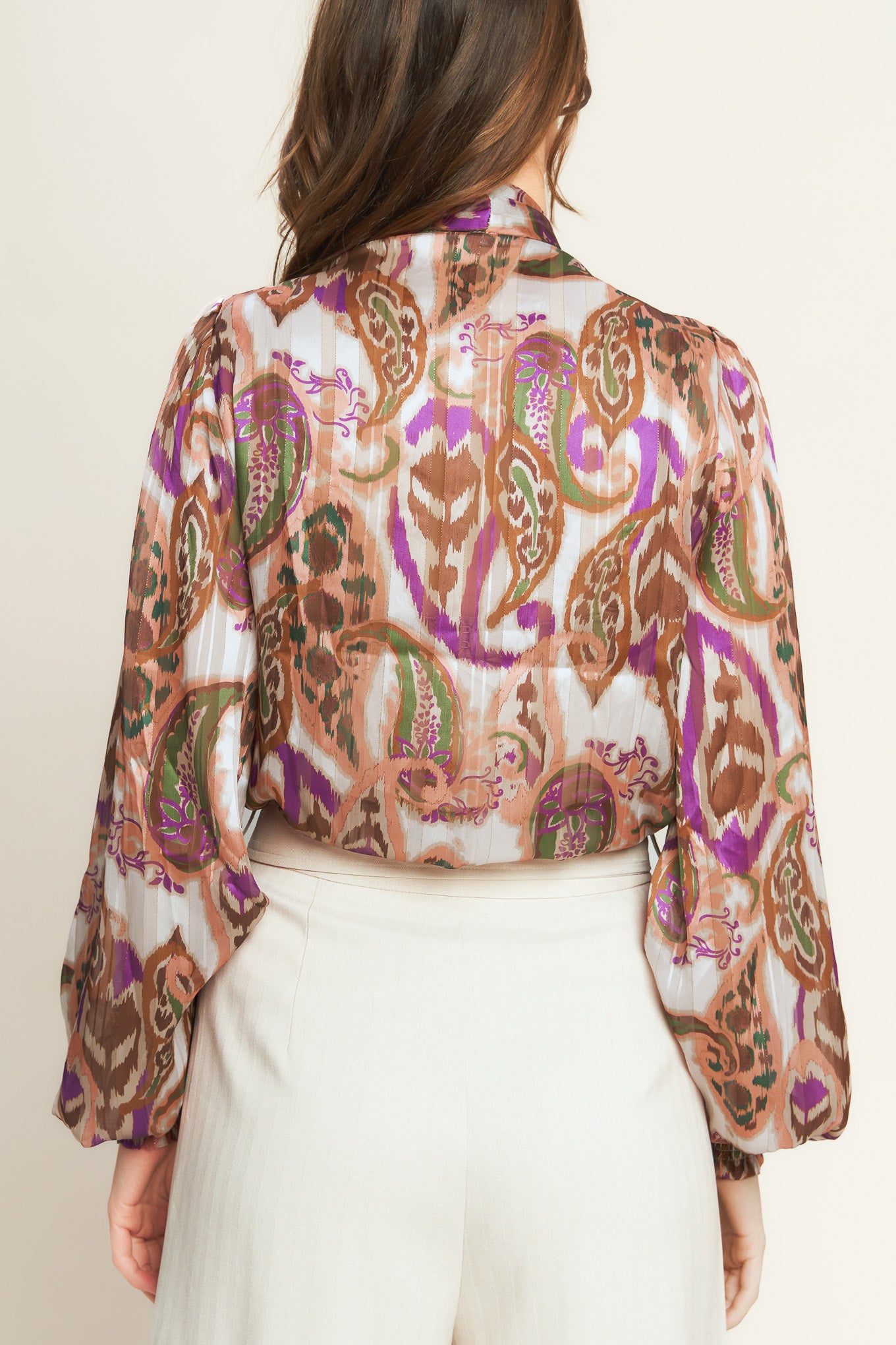 Woman wearing a patterned blouse with a bow tie against a plain background. A printed woven top featuring front bow tie and long sleeve with smocked cuff - FLYING TOMATO