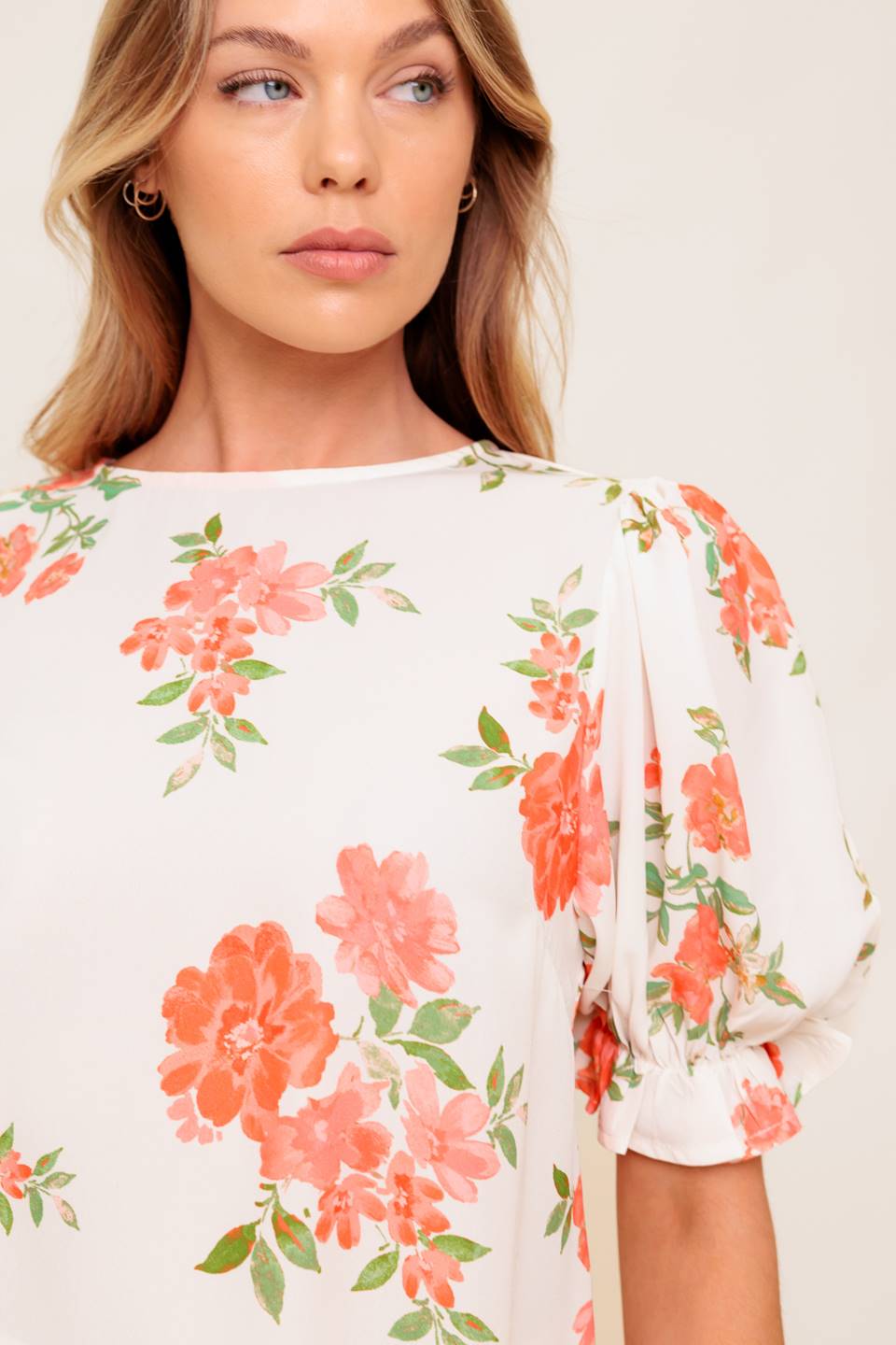 A printed woven top featuring round neckline, short sleeve with ruffled edge and back button closure.