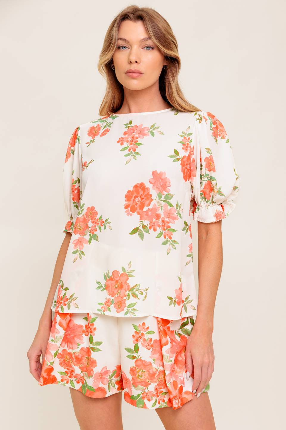 A printed woven top featuring round neckline, short sleeve with ruffled edge and back button closure.
