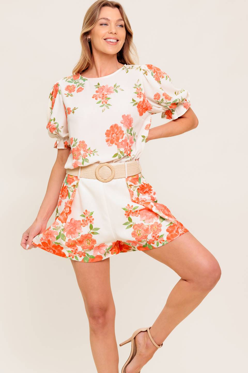 A printed woven top featuring round neckline, short sleeve with ruffled edge and back button closure.