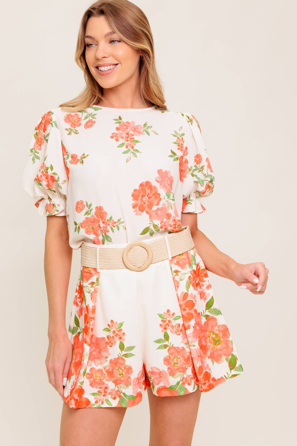 A printed woven top featuring round neckline, short sleeve with ruffled edge and back button closure.