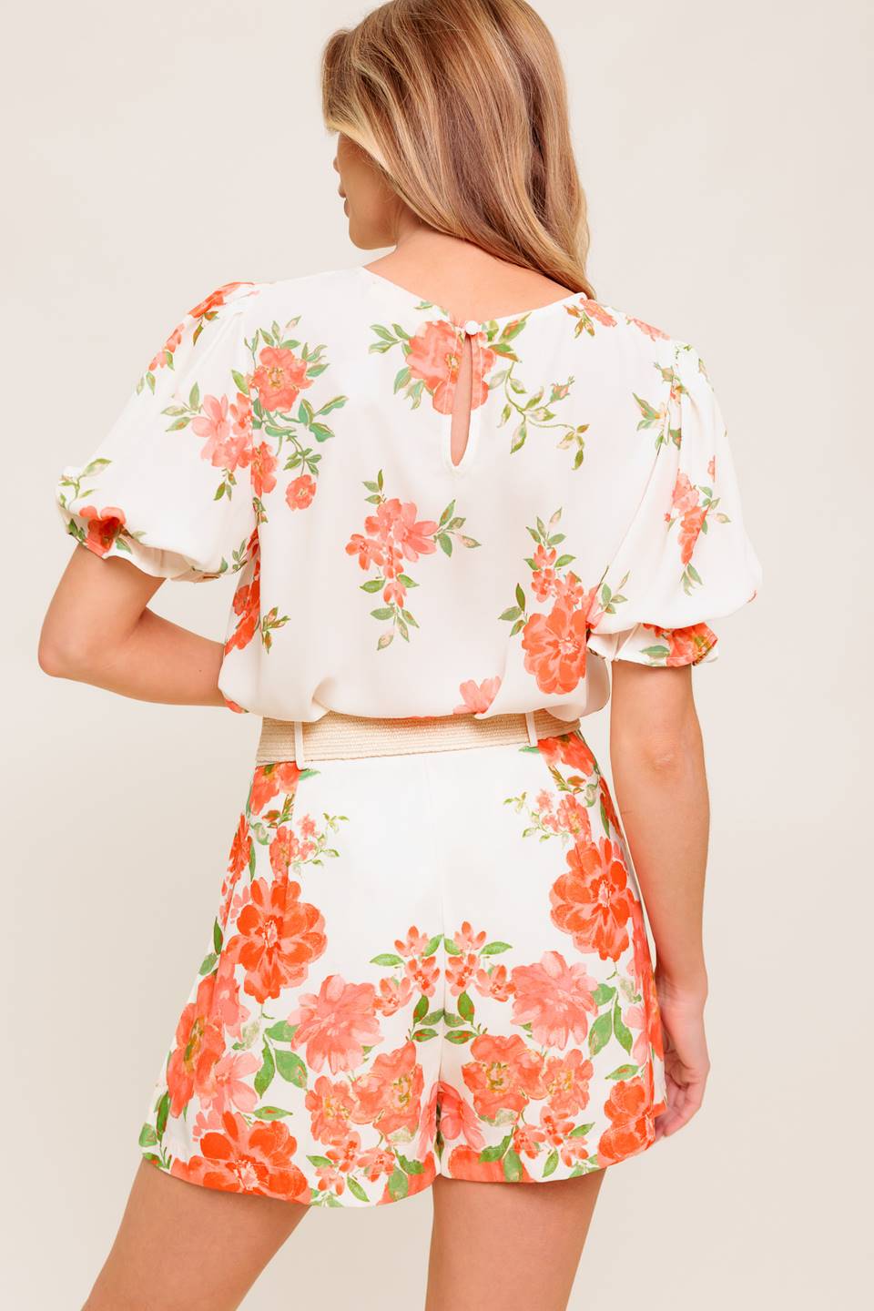 A printed woven top featuring round neckline, short sleeve with ruffled edge and back button closure.