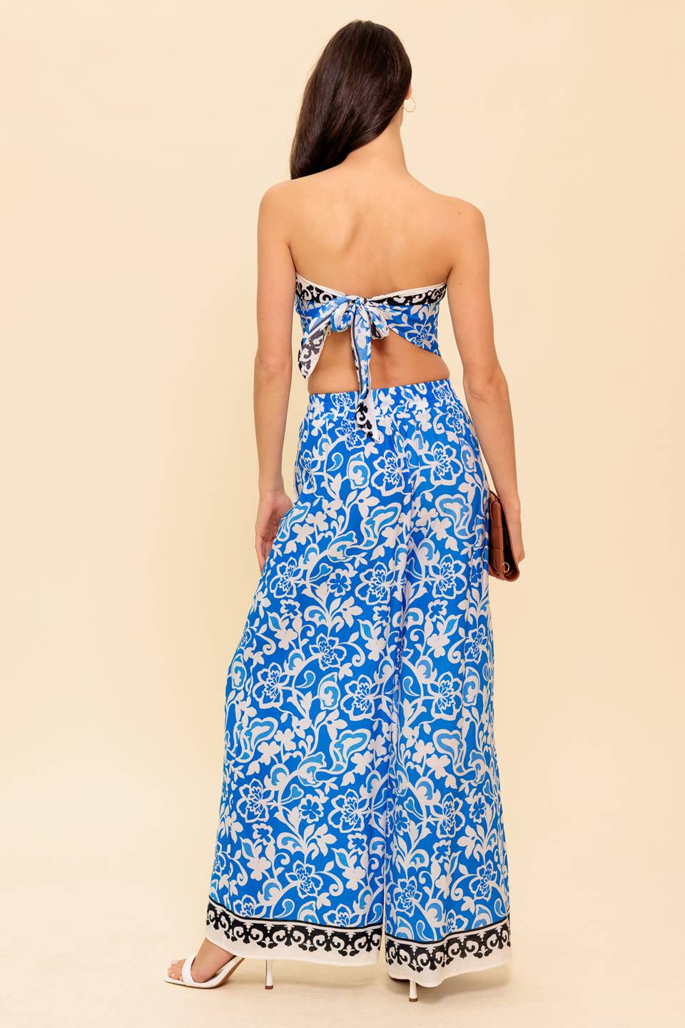 A printed woven top and pant set. Top featuring strapless with back tie. Bottom featuring elasticized waistband with front tie and wide leg
