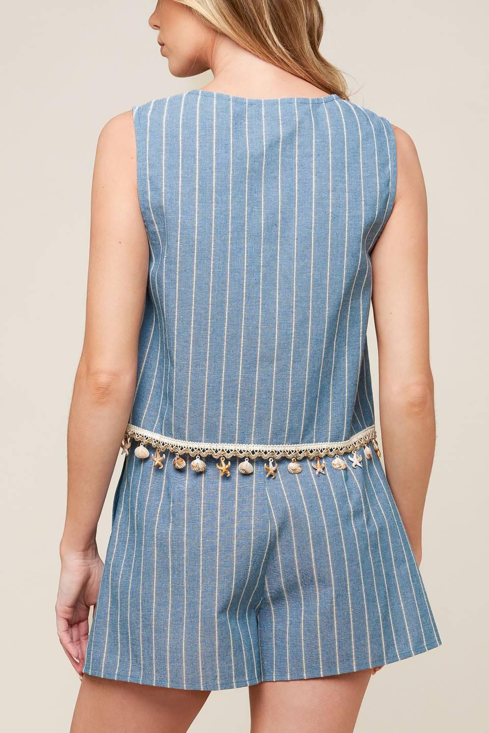 A striped woven top and shorts set. Top featuring front bow ties, sleeveless and seashell trimmed hem. Shorts featuring front closure and side pockets