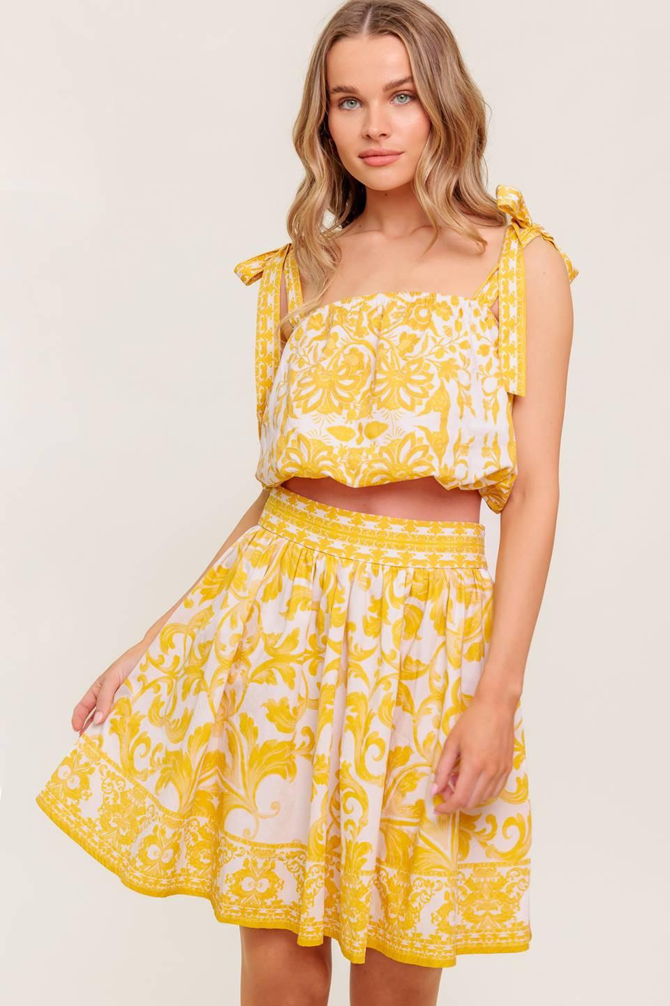 A printed woven top and skirt set. Top featuring straight neckline, shoulder tie and elasticized waist. Full skirt with side zipper closure.
