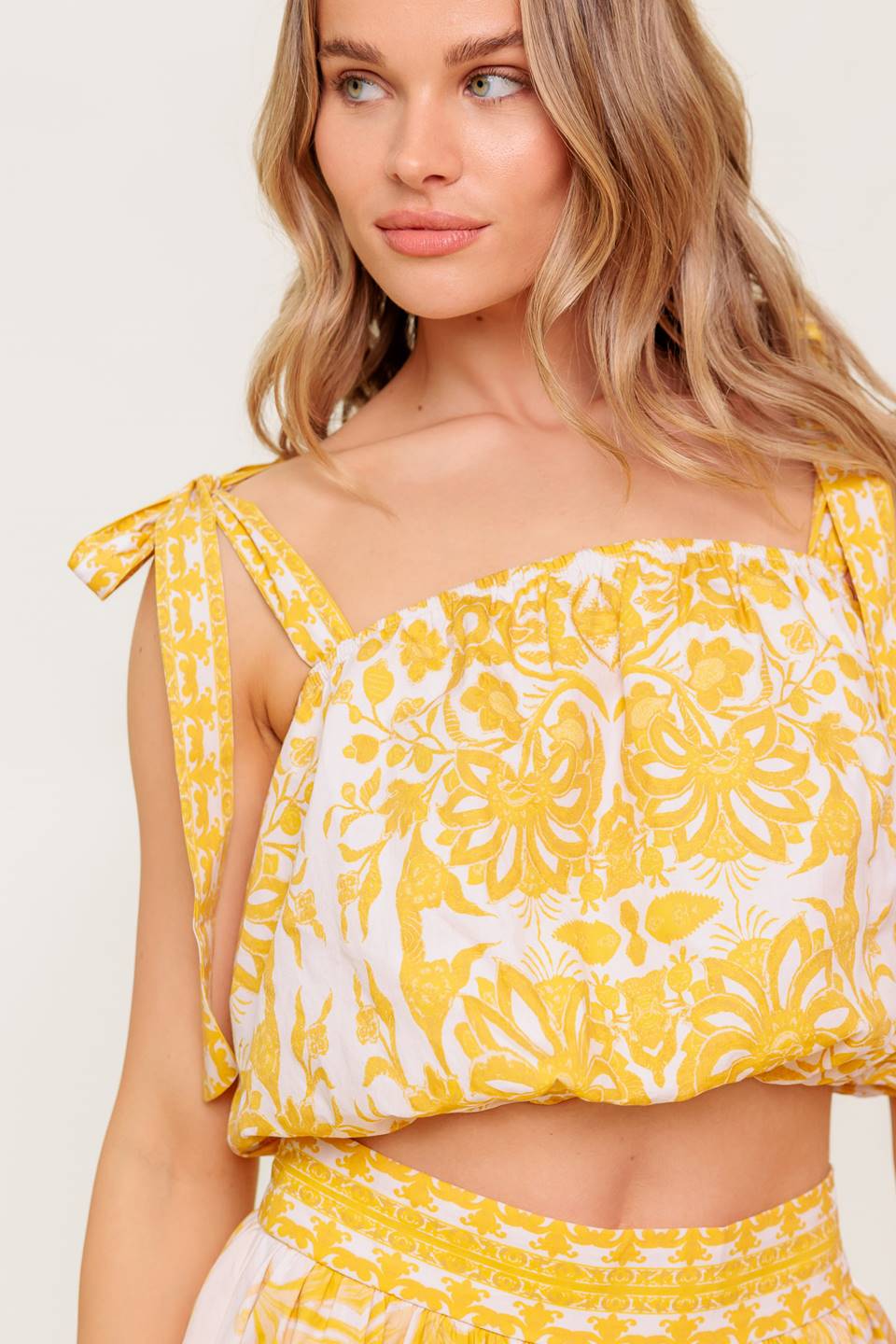 A printed woven top and skirt set. Top featuring straight neckline, shoulder tie and elasticized waist. Full skirt with side zipper closure.