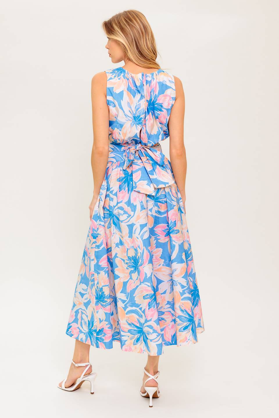 A printed woven top and skirt set. Top featuring side neckline, shirring, sleeveless and back tie and button closure. Full skirt with side zipper closure