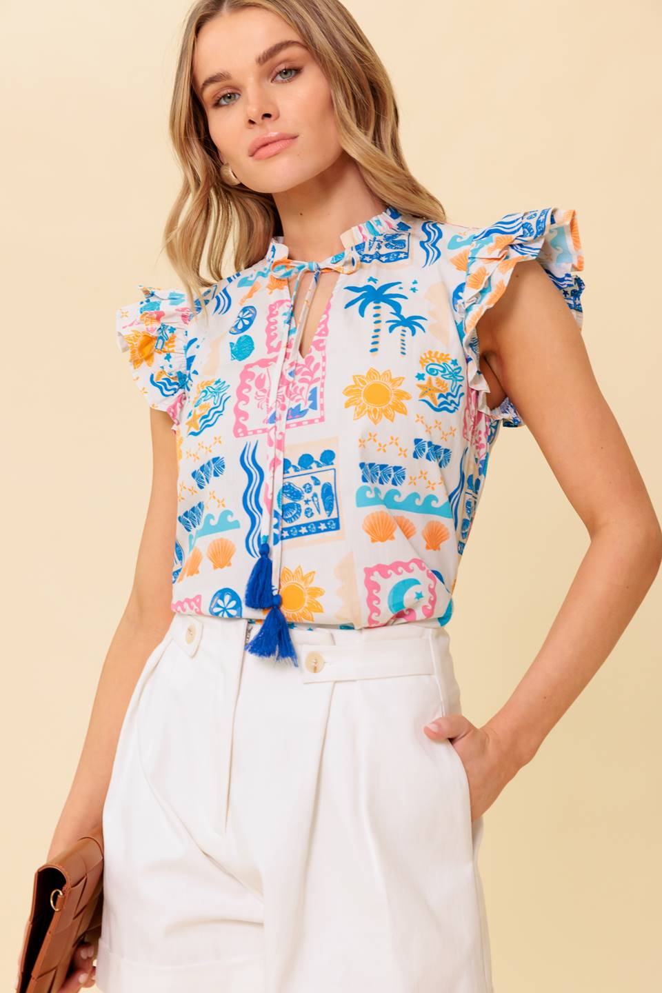 A printed woven top featuring ruffled neckline with front tie and double ruffled sleeve