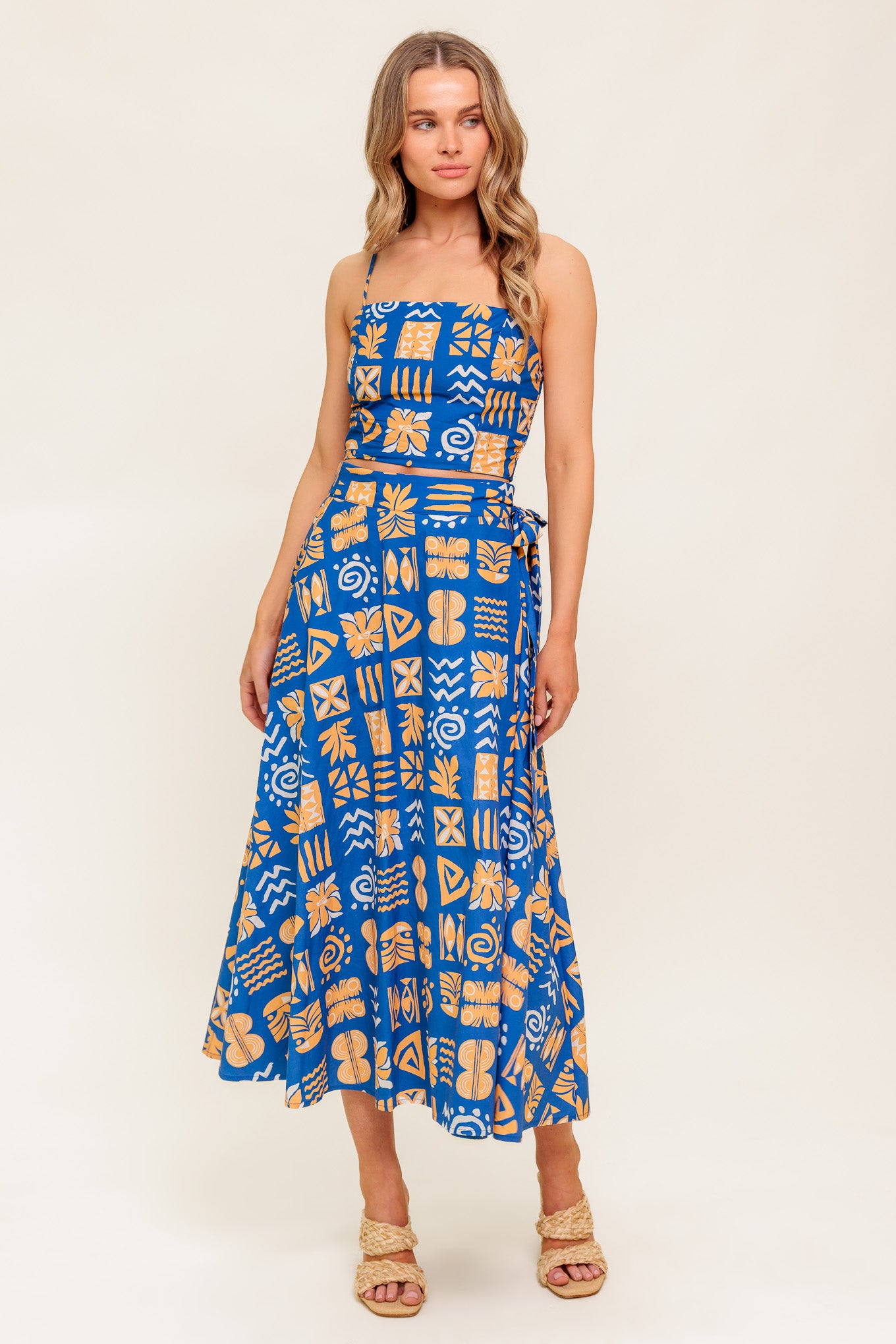 A printed woven top and skirt set. Crop top featuring straight neckline, straps and smocked back bodice. True wrap skirt with side tie