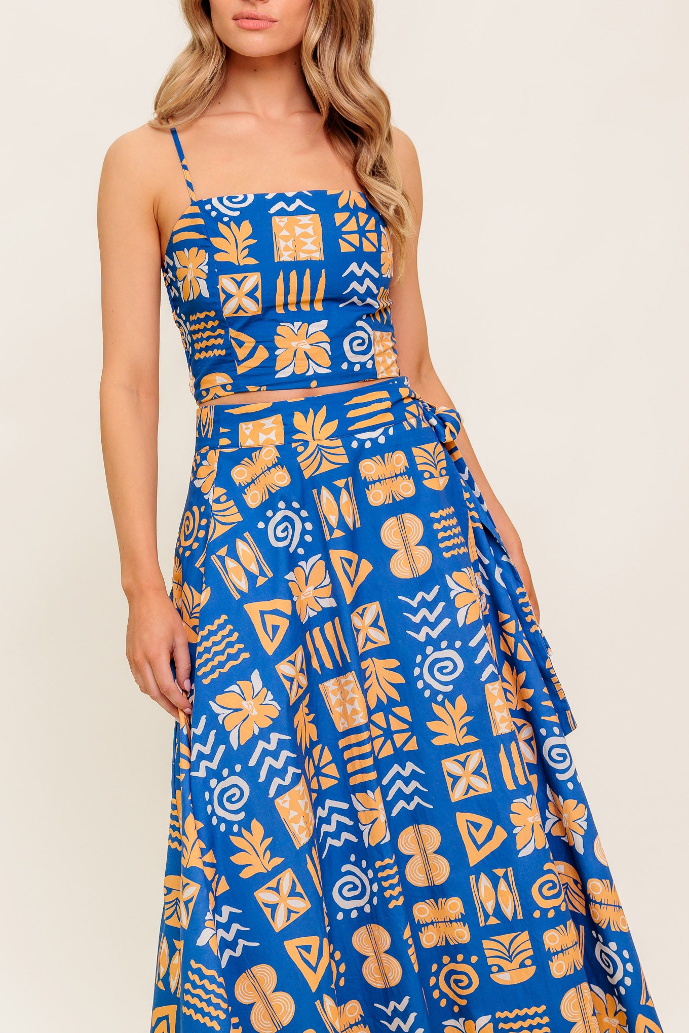 A printed woven top and skirt set. Crop top featuring straight neckline, straps and smocked back bodice. True wrap skirt with side tie