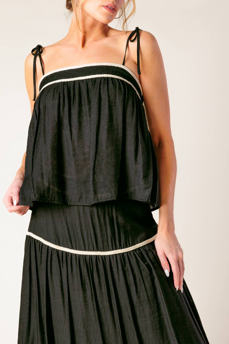 A solid woven top and skirt set. Top featuring straight neckline with straps and smocked back opening. Skirt with side zipper closure