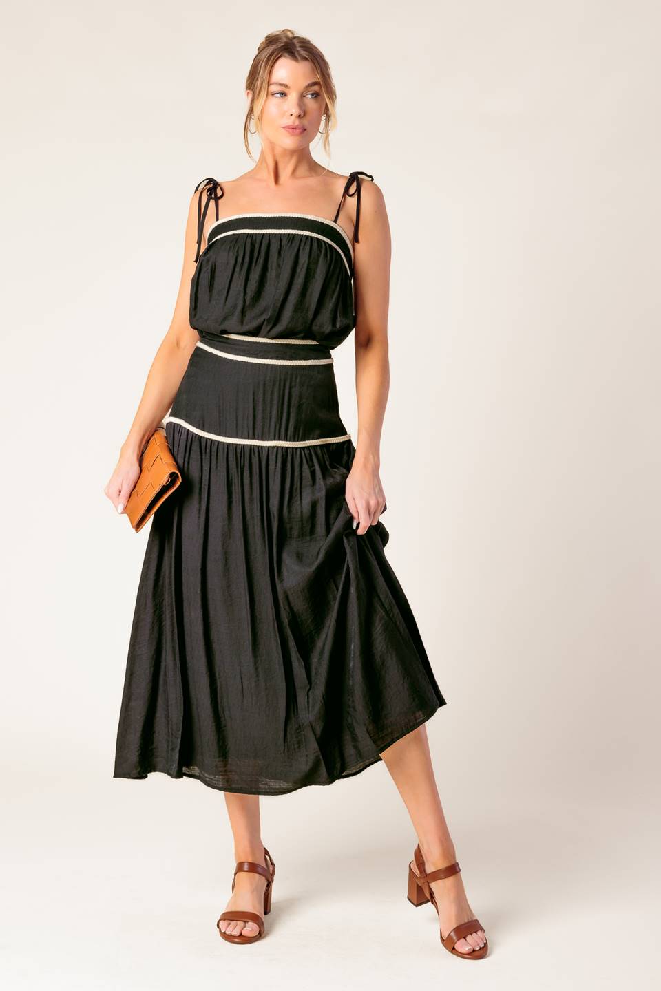 A solid woven top and skirt set. Top featuring straight neckline with straps and smocked back opening. Skirt with side zipper closure