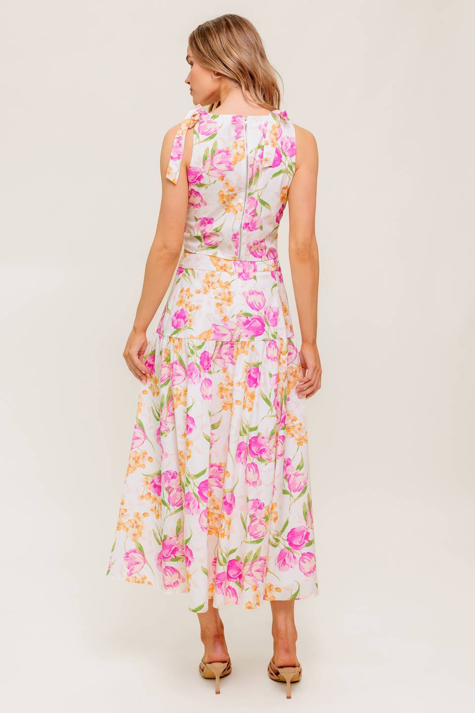 A printed woven top and skirt set. Top featuring crop length, round neckline, sleeveless, shoulder tie and back zipper closure. Midi skirt with side zipper closure.
