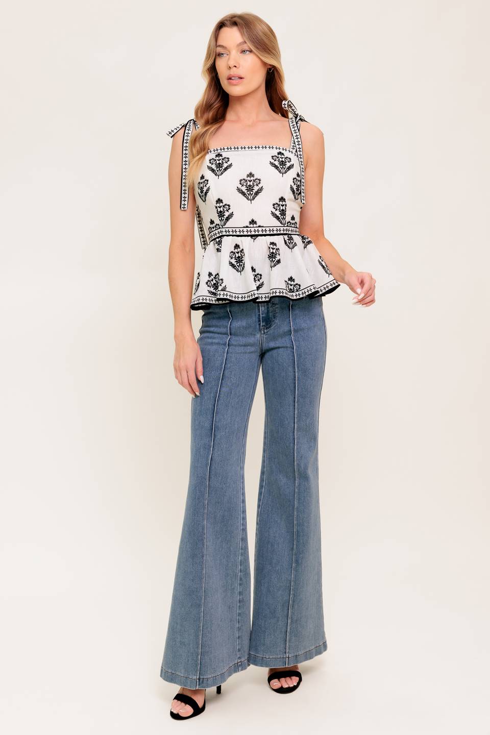 A printed woven top featuring straight neckline, shoulder tie, peplum and back zipper closure.