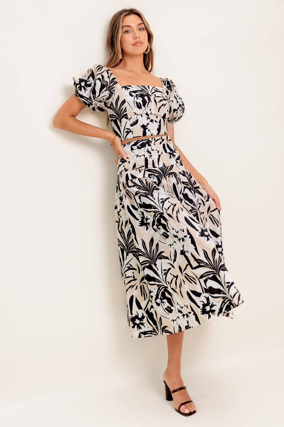 A printed woven top and skirt set featuring square neckline crop top with short puff sleeve and smocked back bodice. Matching skirt with side zipper closure