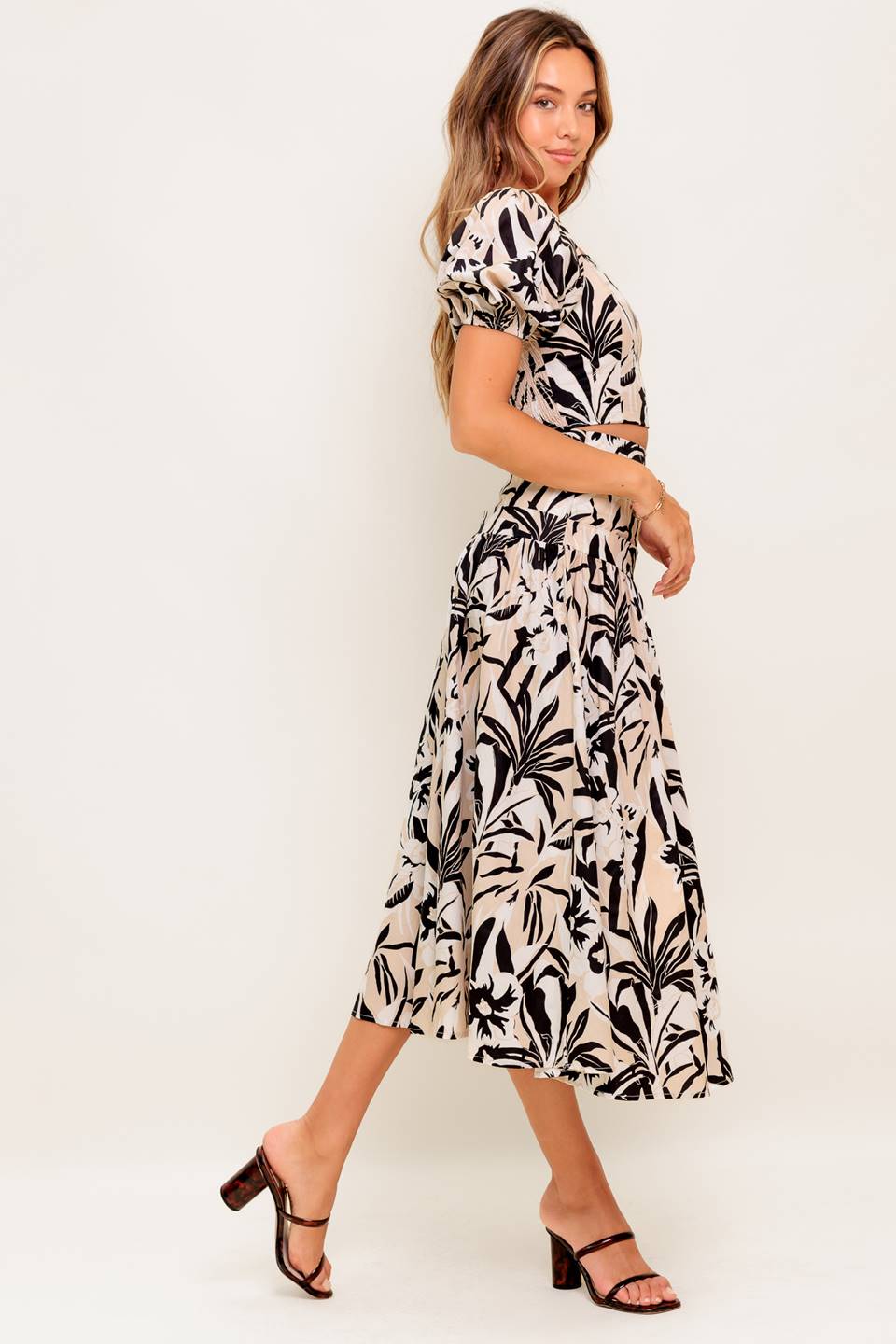 A printed woven top and skirt set featuring square neckline crop top with short puff sleeve and smocked back bodice. Matching skirt with side zipper closure