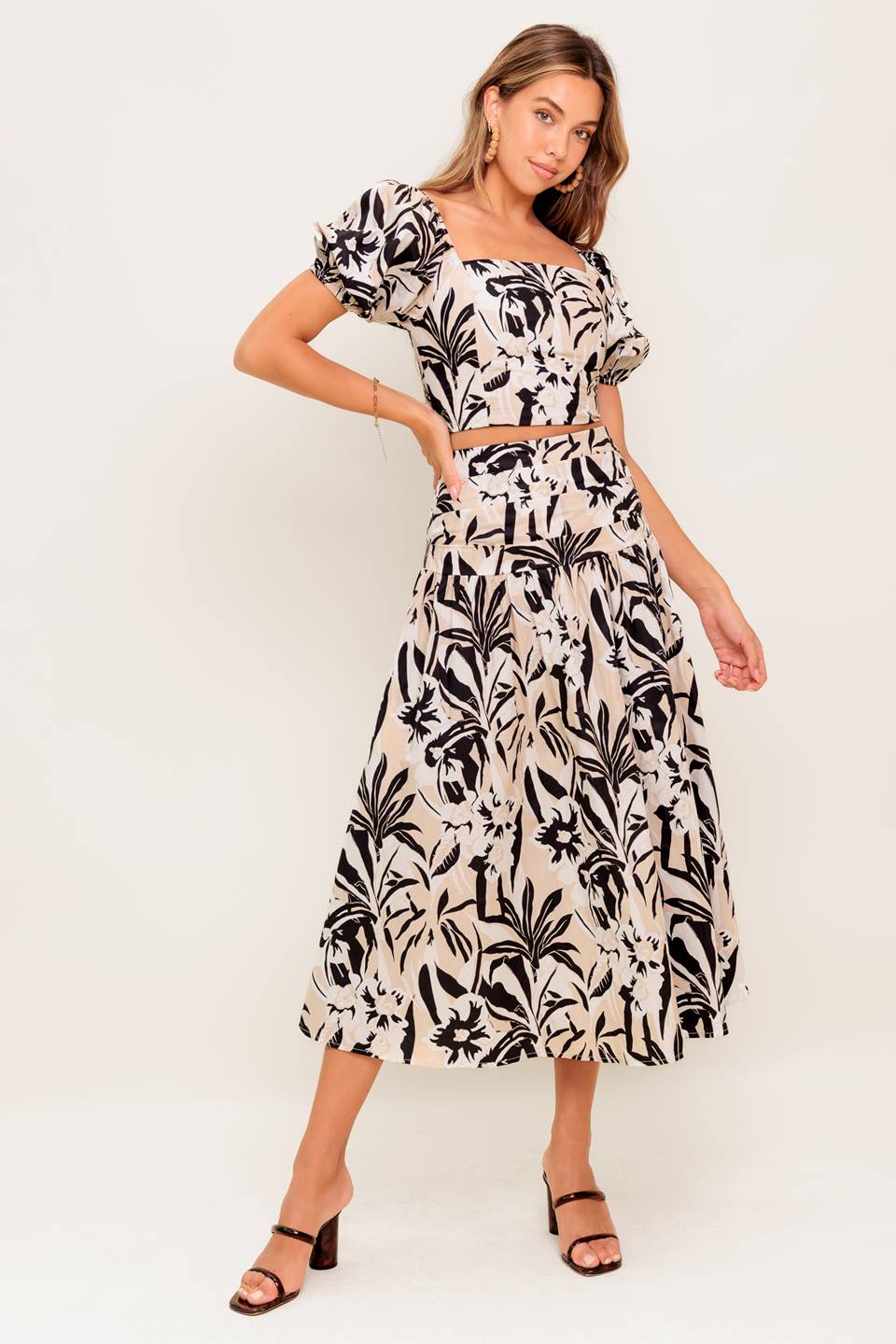 A printed woven top and skirt set featuring square neckline crop top with short puff sleeve and smocked back bodice. Matching skirt with side zipper closure