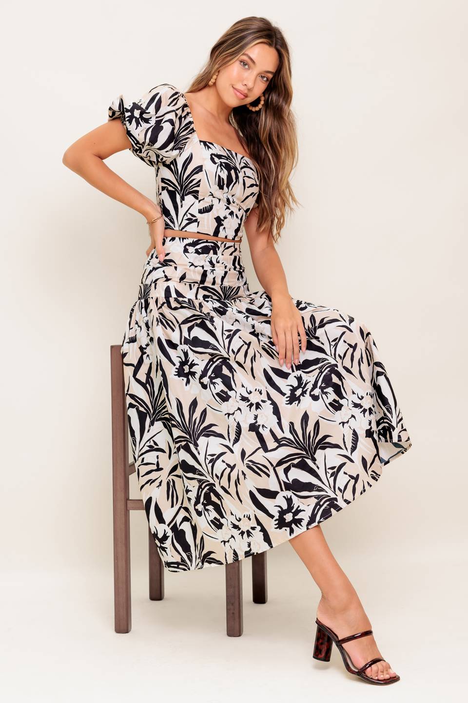 A printed woven top and skirt set featuring square neckline crop top with short puff sleeve and smocked back bodice. Matching skirt with side zipper closure