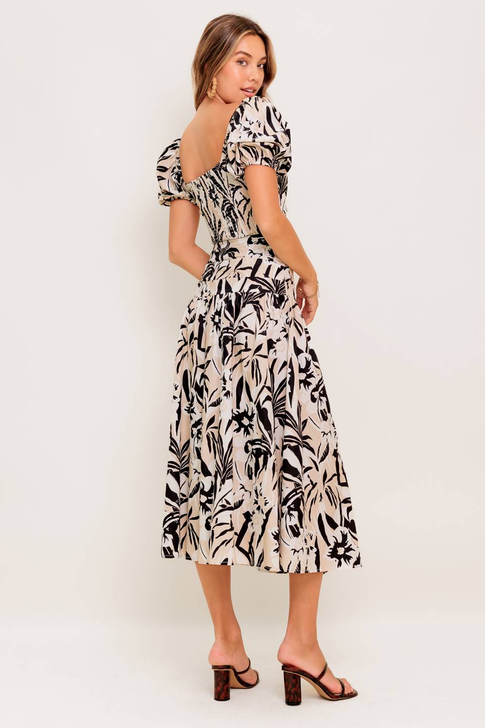 A printed woven top and skirt set featuring square neckline crop top with short puff sleeve and smocked back bodice. Matching skirt with side zipper closure