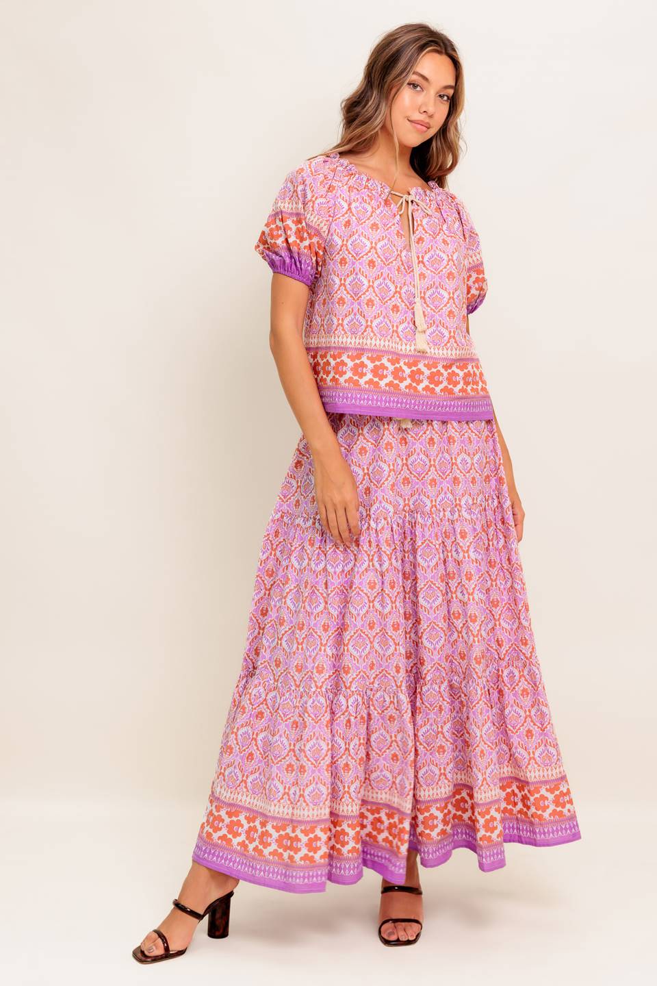 A printed woven top featuring wide neckline with ruffled edge, short sleeve and contrasting tie
