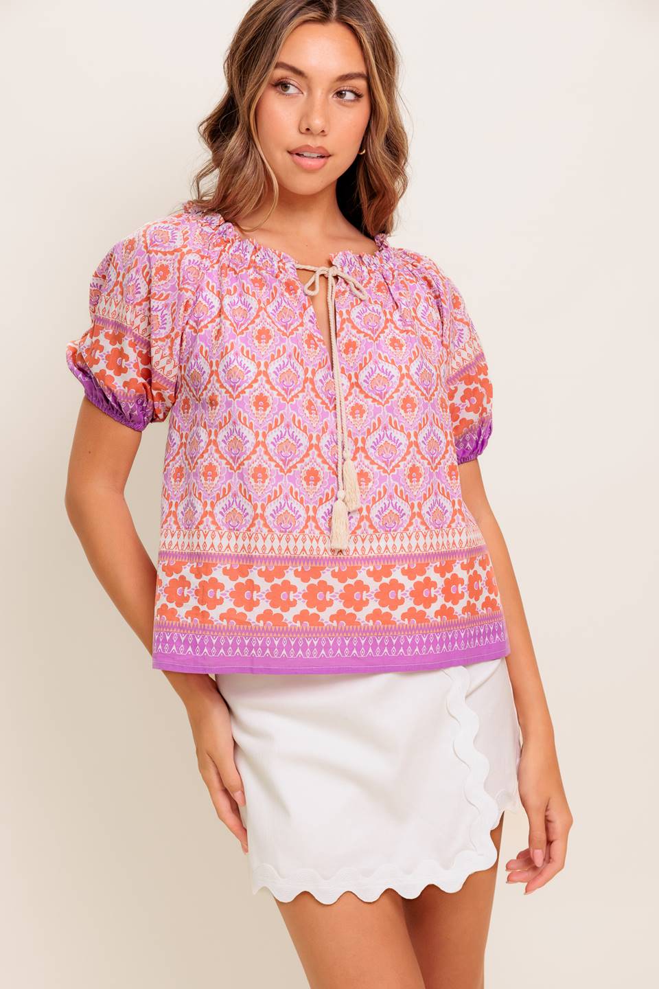 A printed woven top featuring wide neckline with ruffled edge, short sleeve and contrasting tie