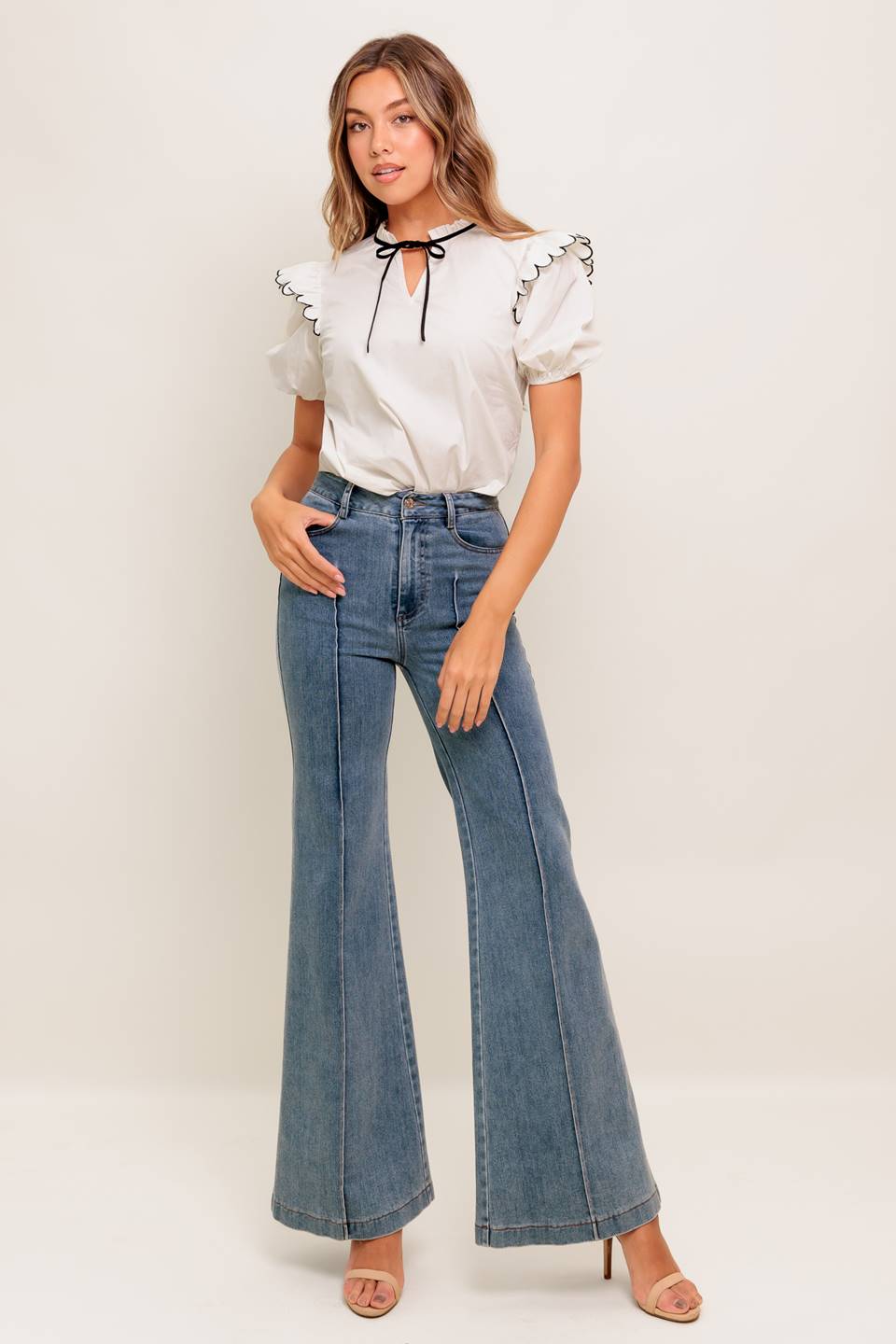 A solid woven top featuring ruffed neckline with tie, scallop edge shoulder and short sleeve