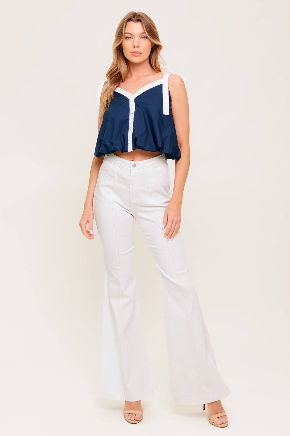 A solid woven top featuring shoulder tie, button detail and bubble hemline.