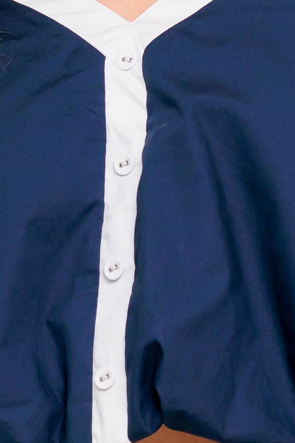 A solid woven top featuring shoulder tie, button detail and bubble hemline.