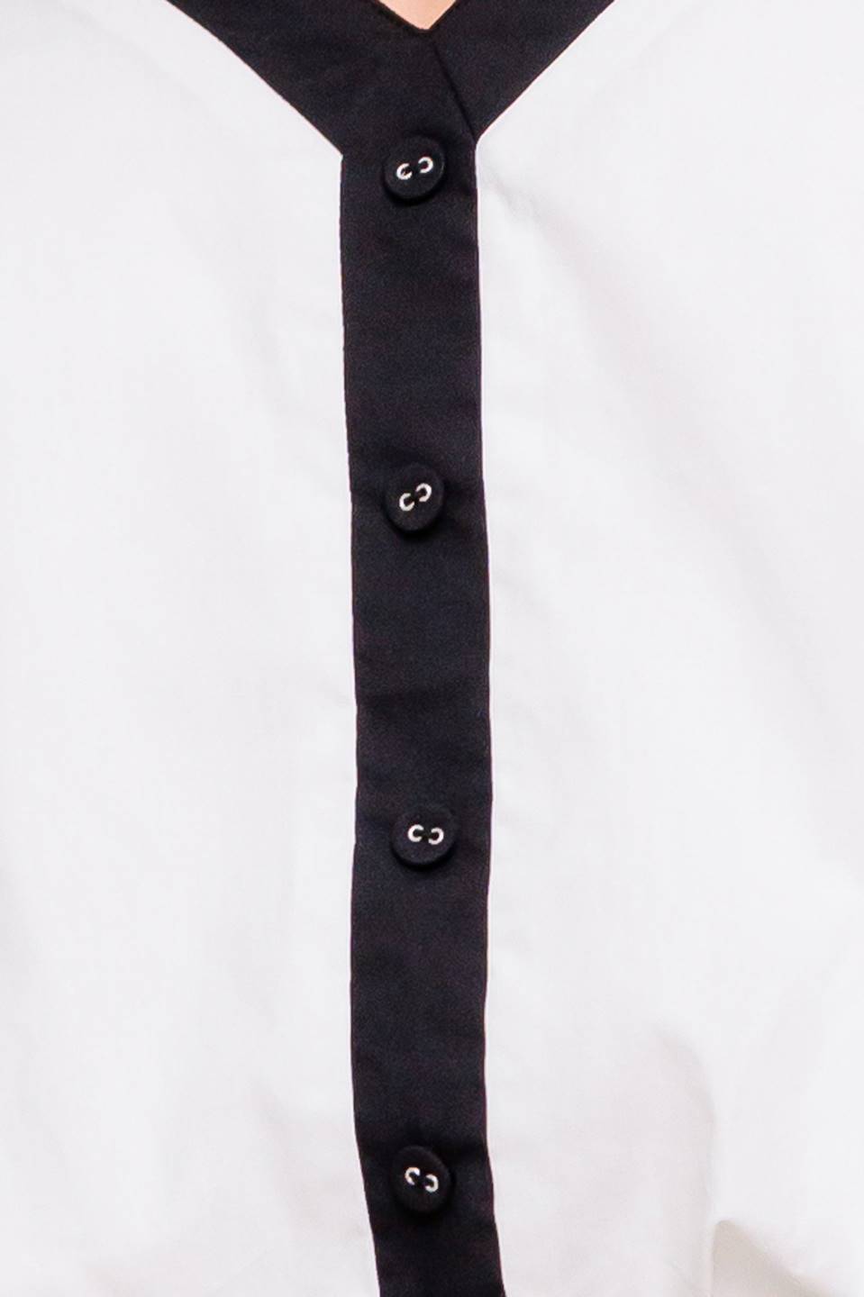 A solid woven top featuring shoulder tie, button detail and bubble hemline.