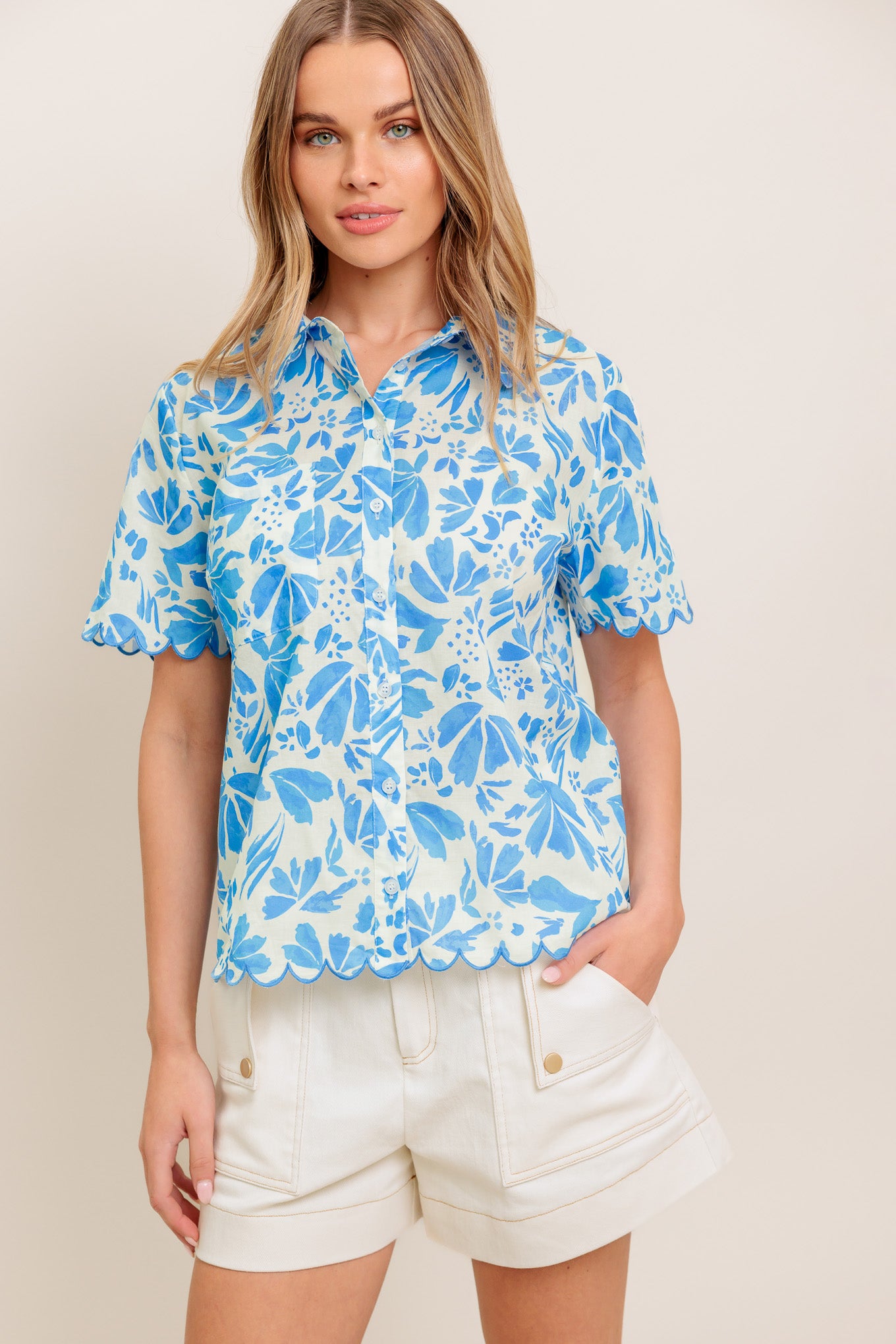 A printed woven top featuring scallop edge, short sleeve and button down